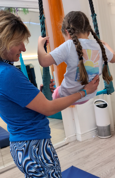 A female teacher helping a young girl on a trapeze