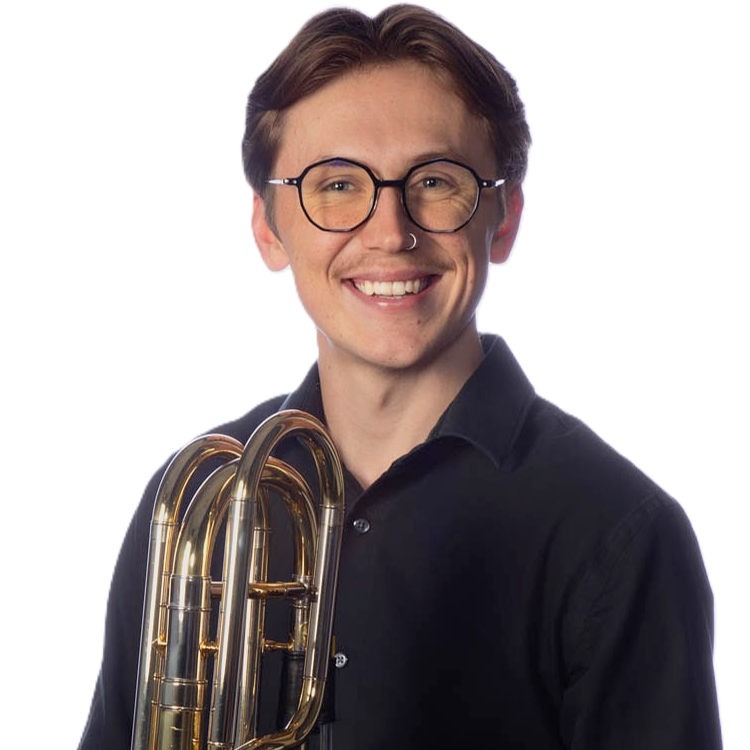 A young woman with short brown hair, wearing glasses and a nose ring, is smiling at the camera and holding a brass euphonium.
