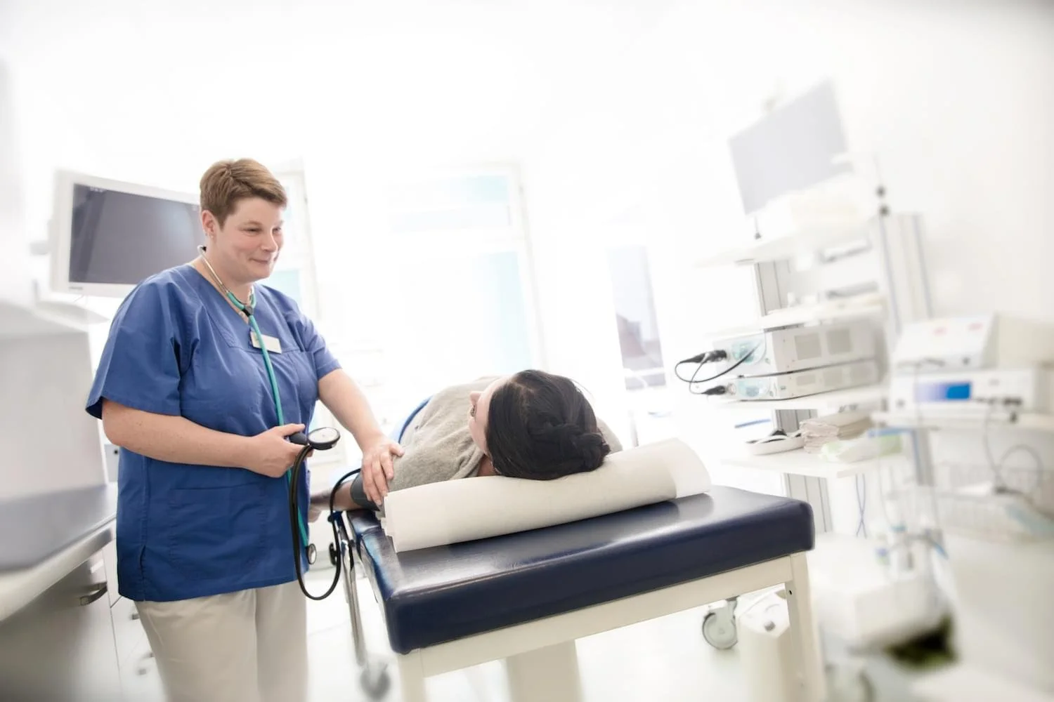 Krankenschwester überprüft Patientin im Krankenhausbett.