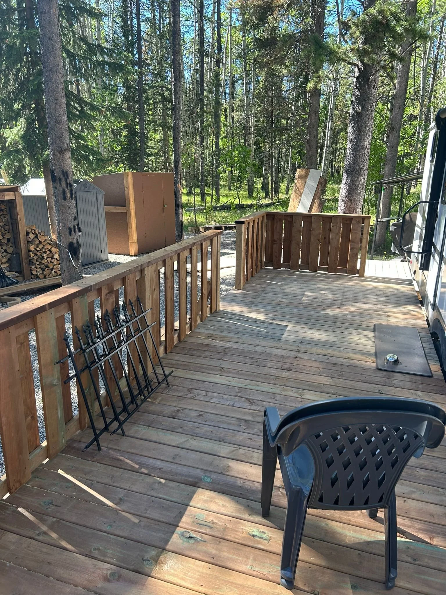 Wide elevated wood deck installation on a seasonal RV lot with an alternating dark and natural wood railing and an integrated walkway platform