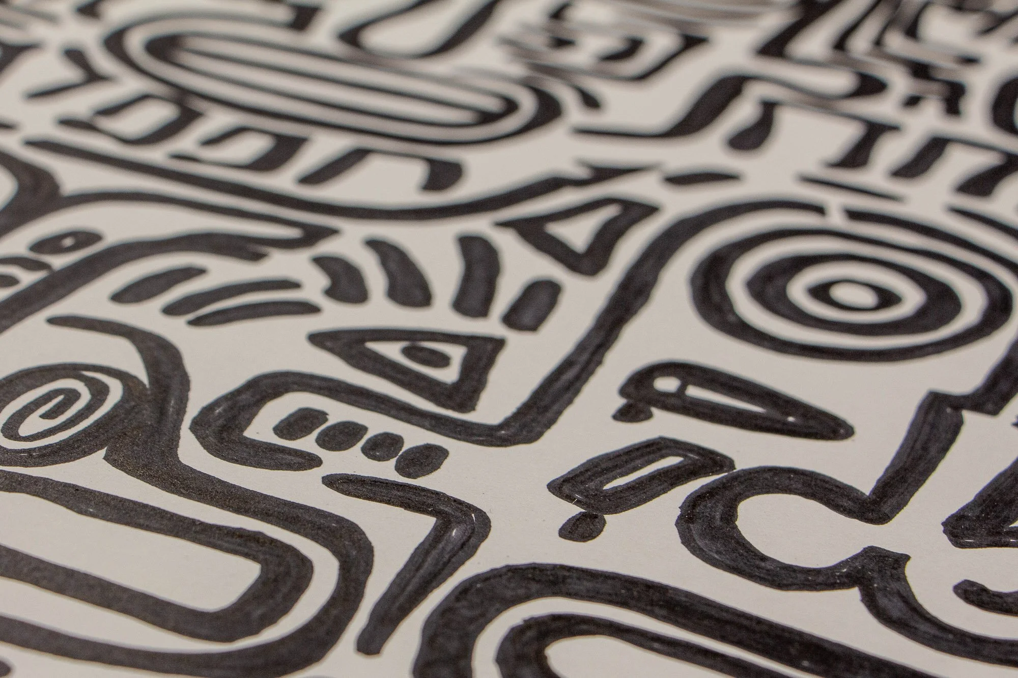 Mêlée of Discovery 004: angled surface detail of abstract faces and concentric eye motifs, revealing the flowing black linework as it moves across the white paper.