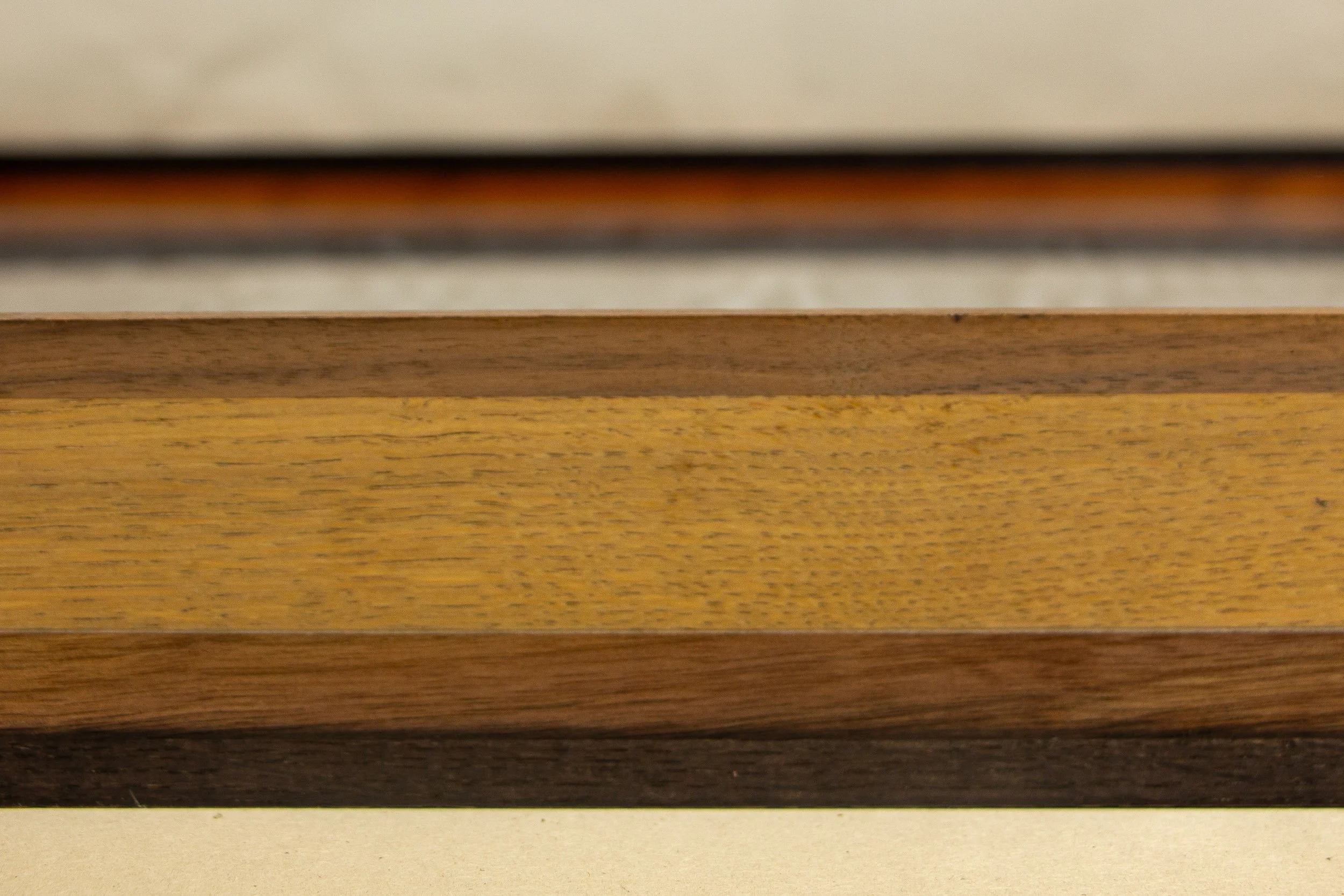 Mêlée of Discovery 001 frame: angled close-up of the frame corner and side, highlighting its depth, precise join, and the shift from darker outer bands to the broader lighter middle section.