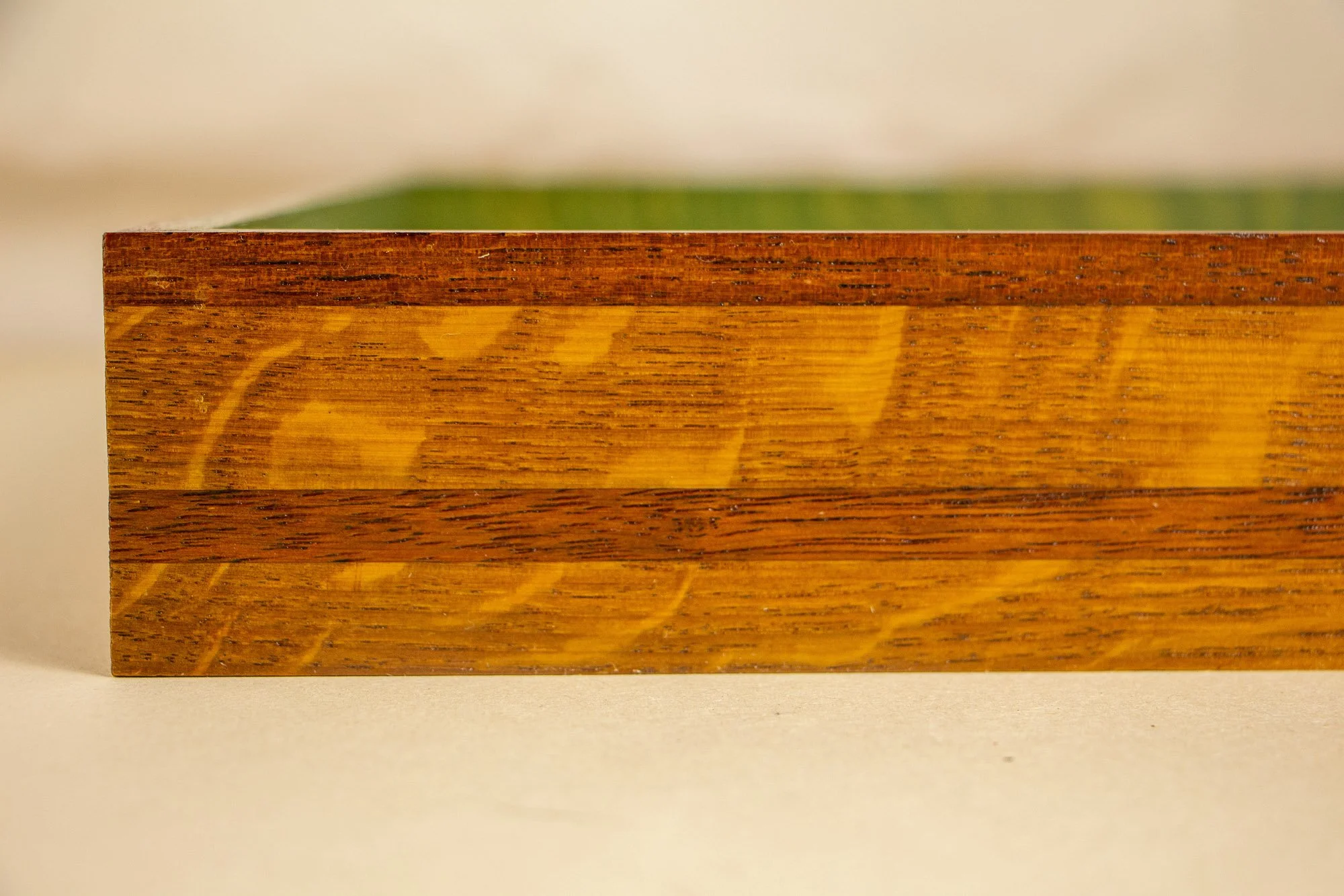 Unseen Signifiers 002 frame detail: straight-on close-up of the frame front, showing the layered construction with a dark top band, warm golden-brown wood, and a darker horizontal strip through the centre. mahogany, oak and beech wood.