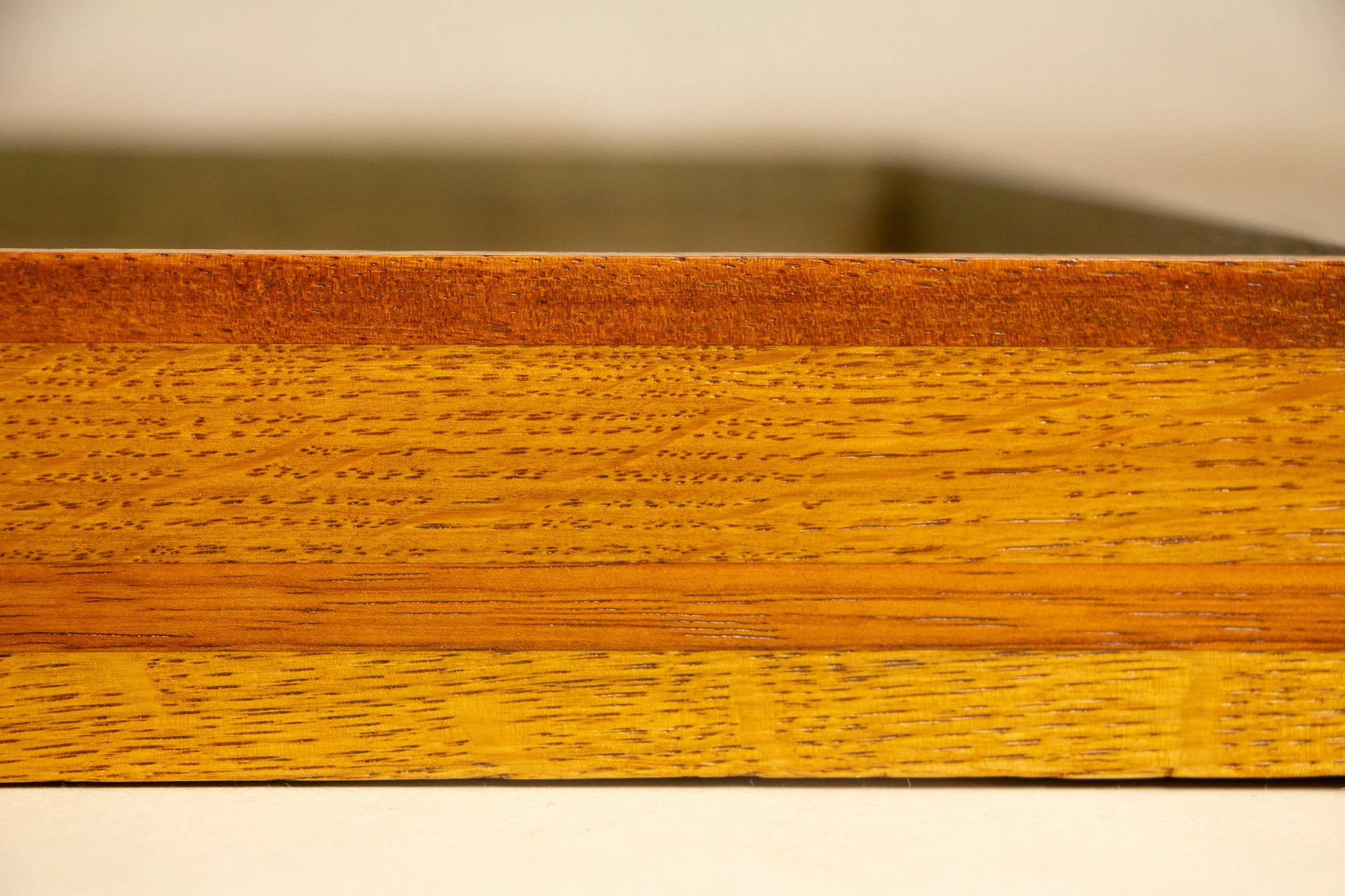 Unseen Signifiers 006 frame detail: close-up of the upper front edge of the frame, focusing on the thin reddish-brown top strip and the broad golden wood band beneath it. mahogany, oak and beech wood.