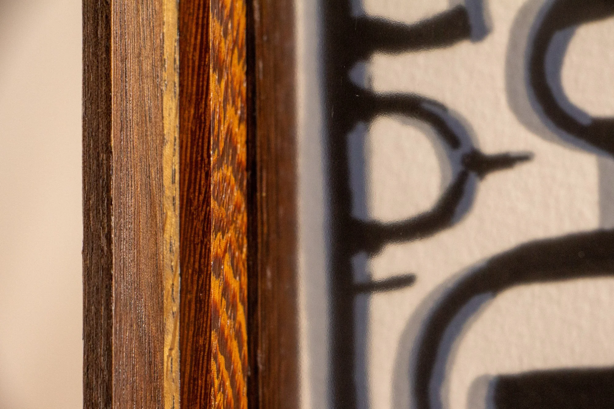 Luminous Parallax 002 frame: close-up of the frame’s vertical inner edge, showing the stacked wood layers beside the glazing and the warm, vividly figured inner recess.