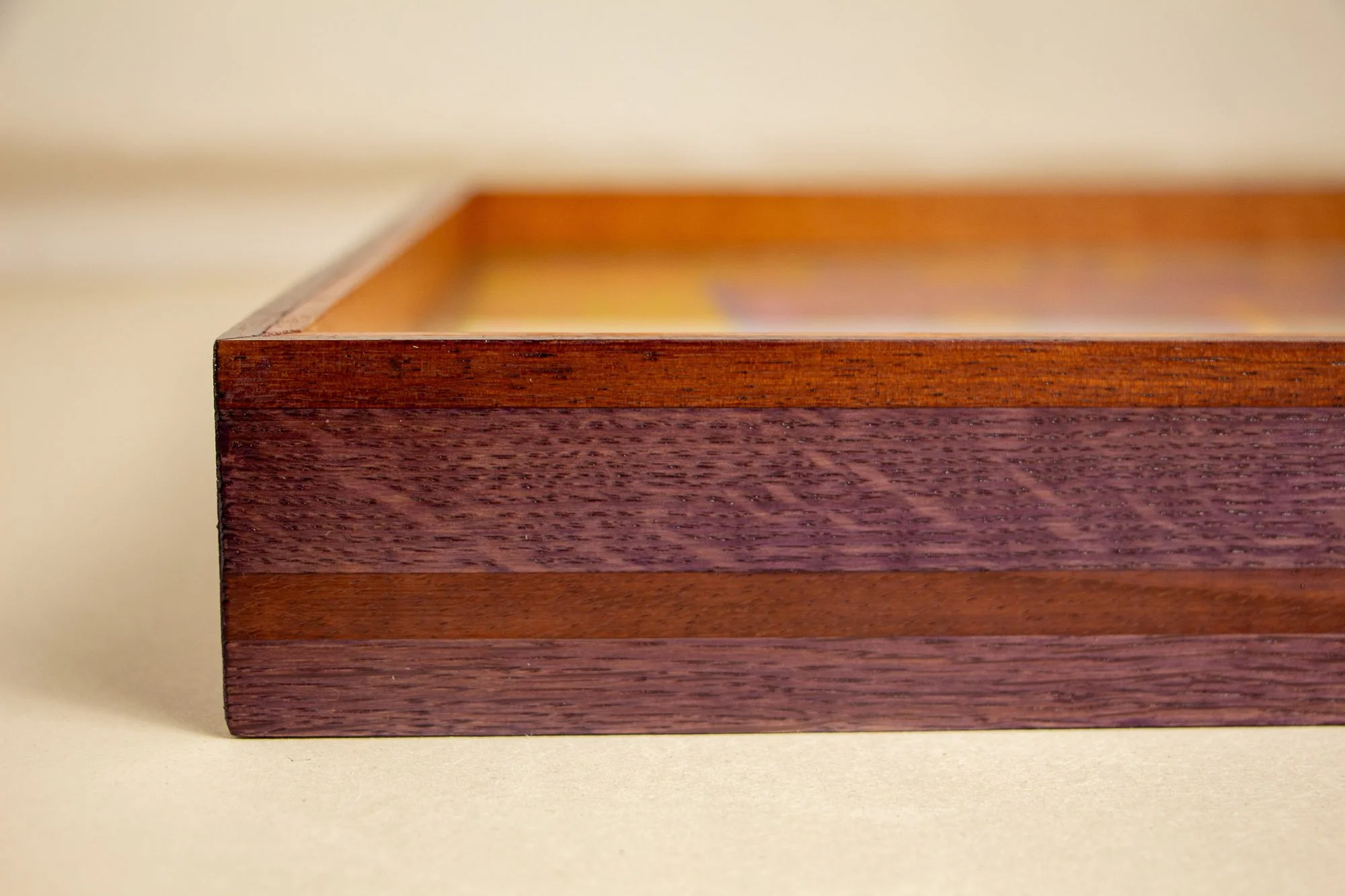 Unseen Signifiers 009 frame detail: front-facing close-up of the frame corner, showing the slim upper edge and the striped construction in plum-toned wood with a warm brown inlay. mahogany, oak and beech wood.