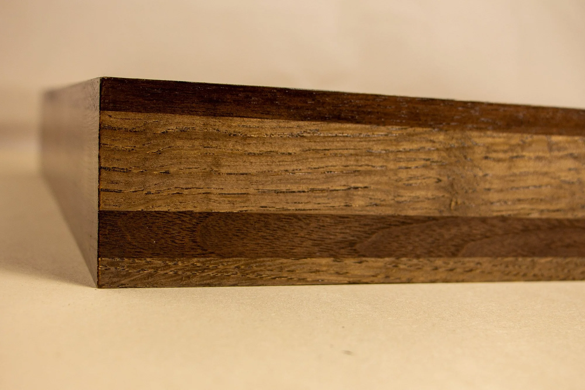 Luminous Parallax 002 frame: straight-on side detail of the frame profile, showing layered woods in dark brown and warm mid-tones, with the banding running cleanly across the length.