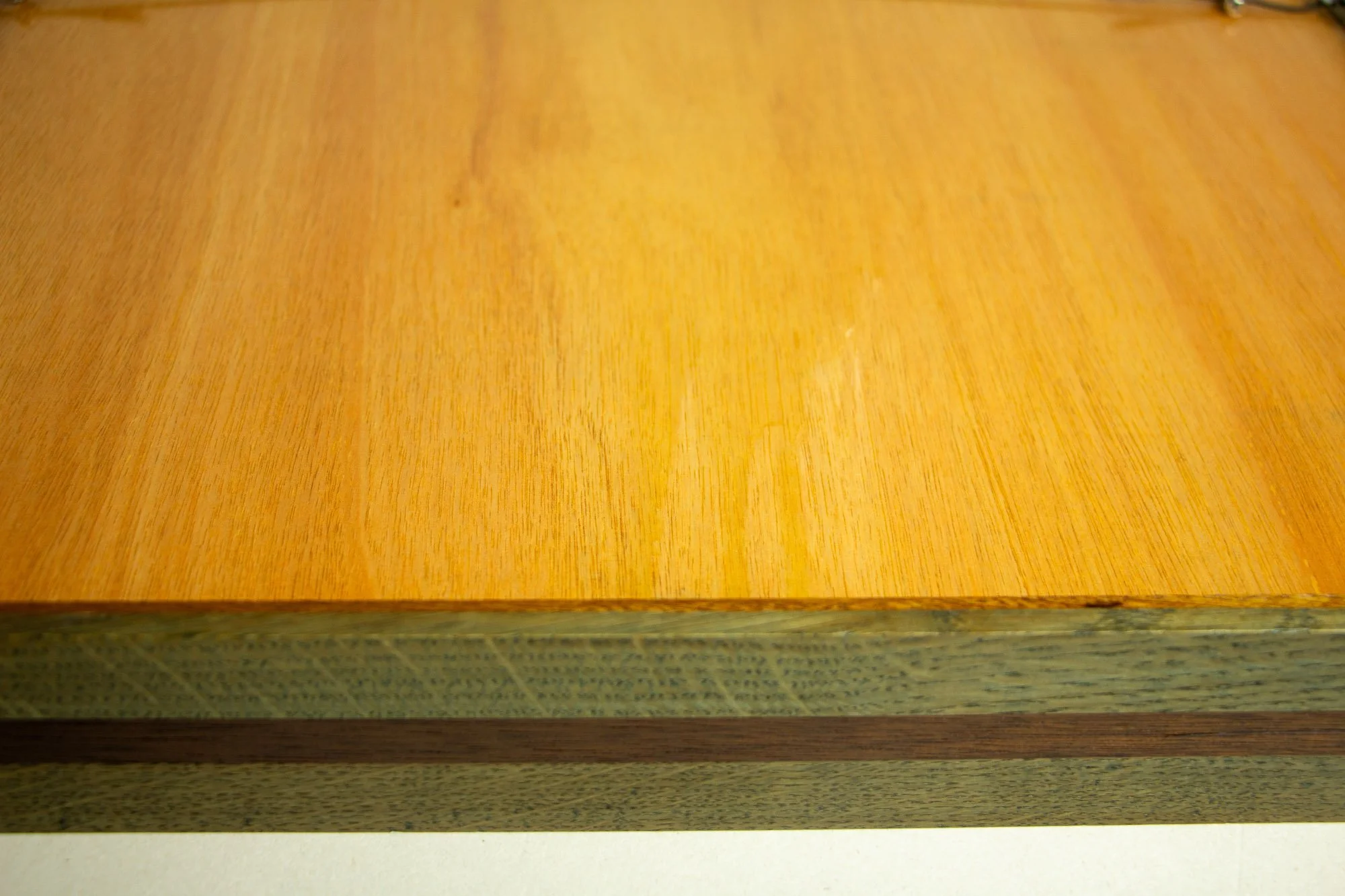 Eclipsing Gravitas 002 frame verso: back detail of the frame with warm meranti plywood back panel and the layered oak-and-mahogany outer edge visible along the lower side.