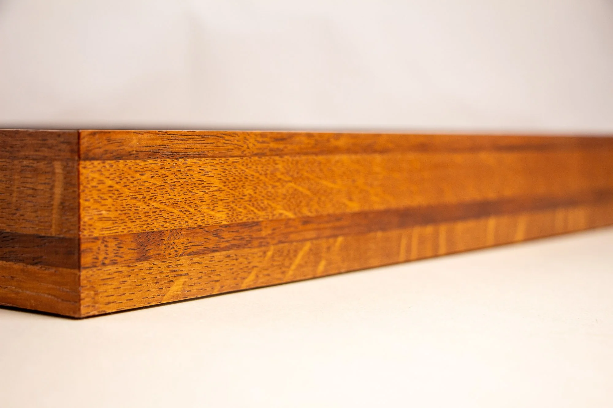 Turbulent Aegis 002 frame detail: angled close-up of the frame edge, revealing the crisp outer line, continuous grain flow, and the balanced transition between lighter and darker wood layers.