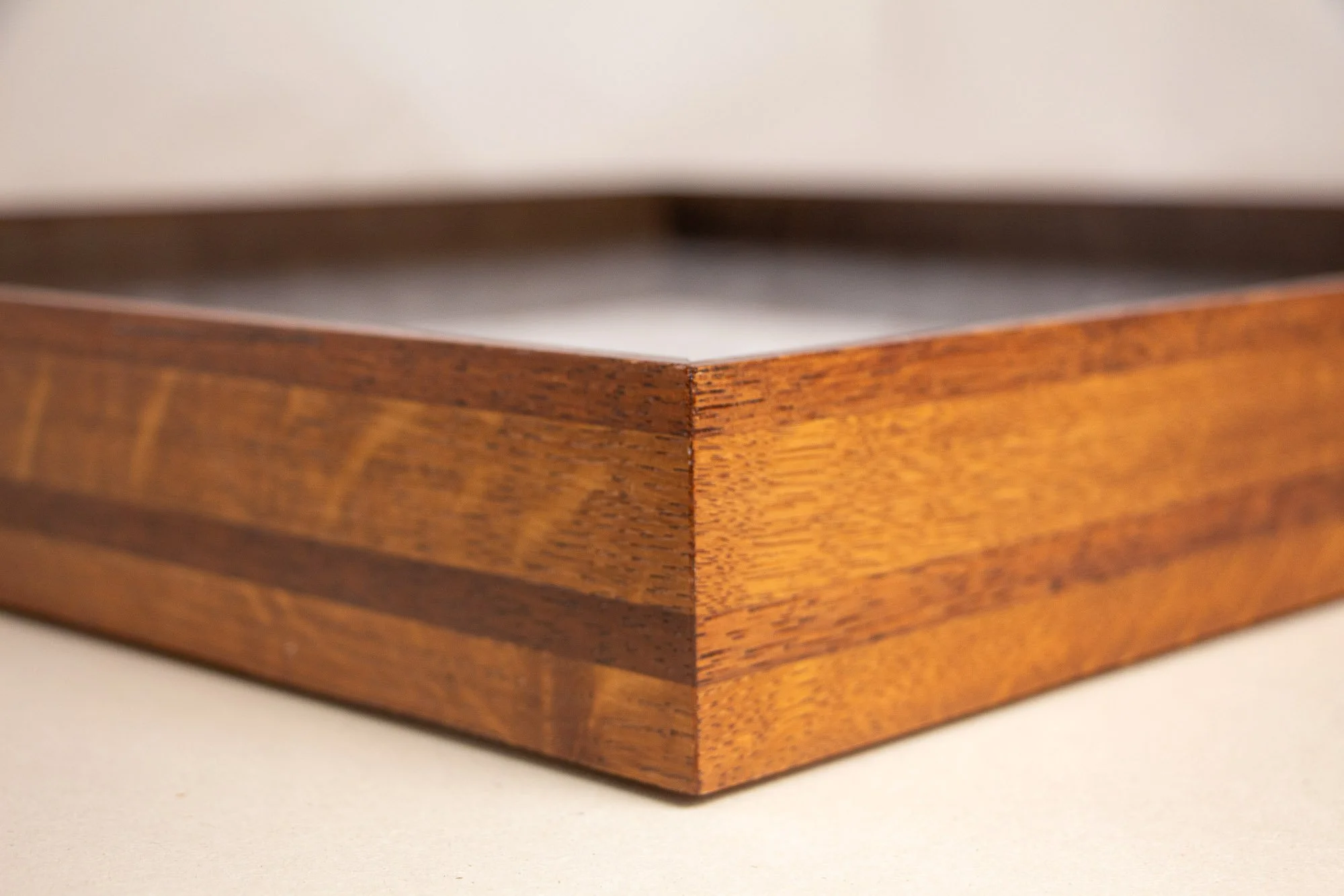 Turbulent Aegis 002 frame detail: angled corner close-up showing the sharp miter joint, layered tonal banding, and polished handcrafted finish of the frame body.