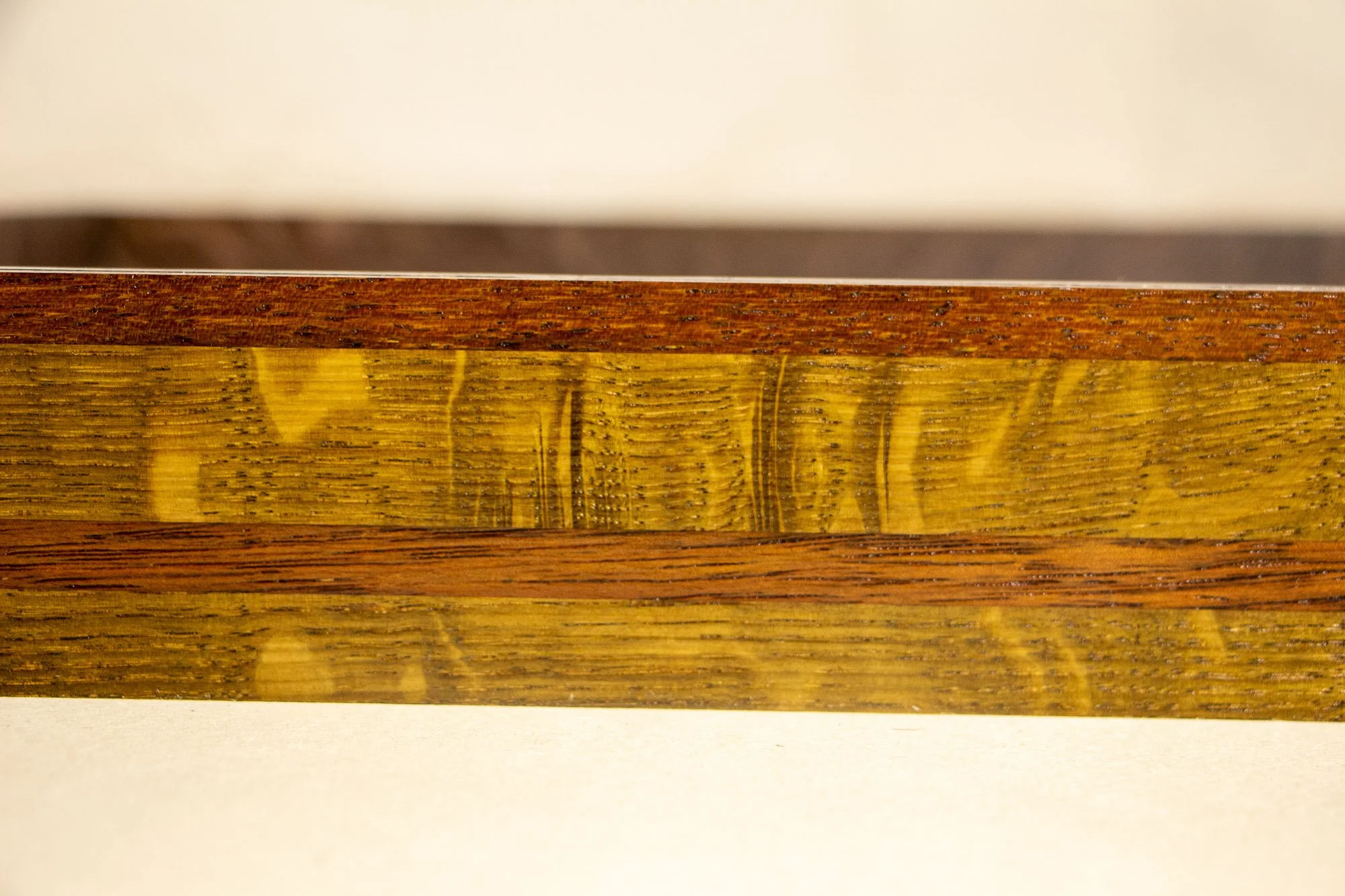 Unseen Signifiers 007 frame detail: frontal close-up of the striped wooden frame, highlighting the contrasting grain patterns and alternating reddish-brown and olive-gold bands. mahogany, oak and beech wood.