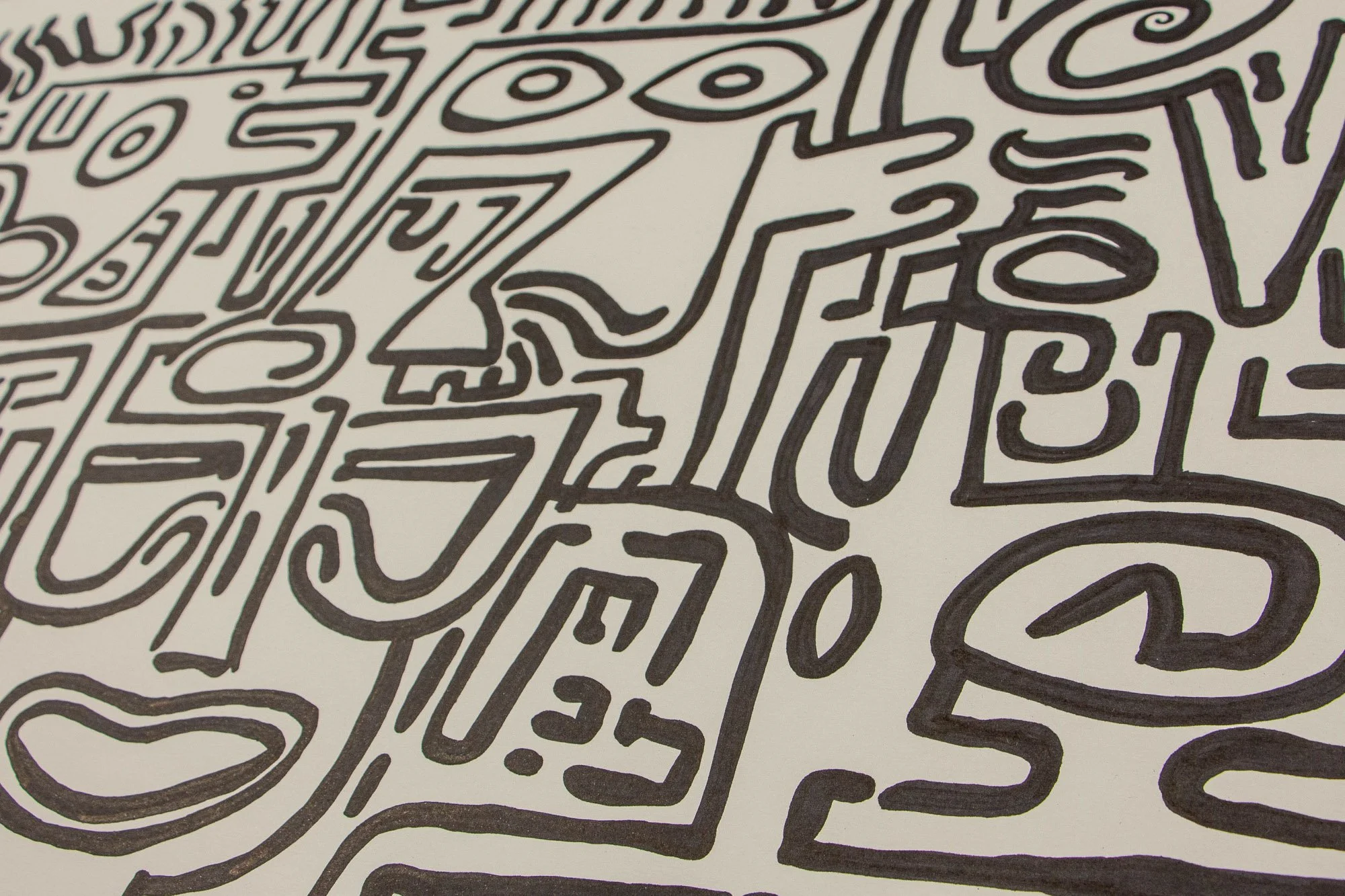 Resonant Syntax 001 detail: raking close-up of clustered glyphs, curved mouths, and stepped facial fragments; dense black contours on paper
