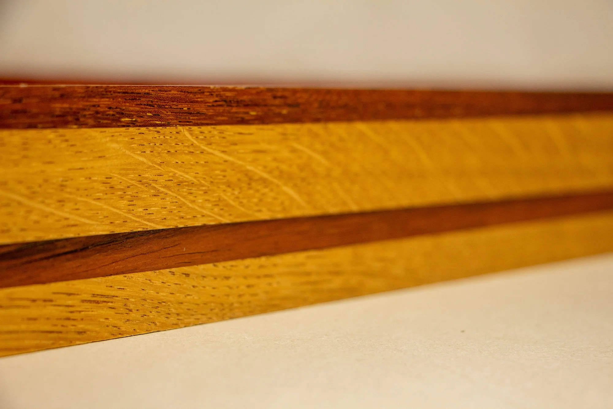 Unseen Signifiers 004 frame detail: angled corner close-up from above, showing the mitred outer frame in warm red-brown wood and the muted olive-green inner reveal around the artwork. mahogany, oak and beech wood.