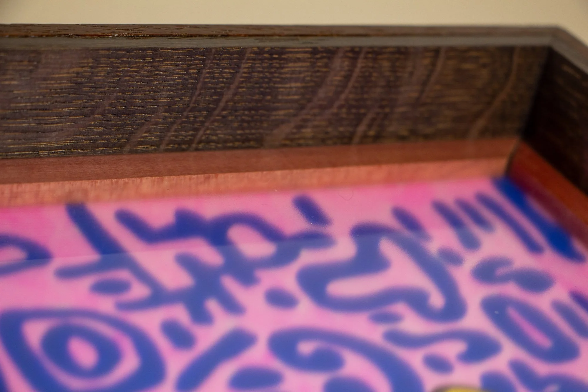 Unseen Signifiers 007 frame detail: oblique close-up of the upper inner frame, emphasizing the dark linear grain, reddish inner border, and the artwork receding softly below the glass. mahogany, oak and beech wood.