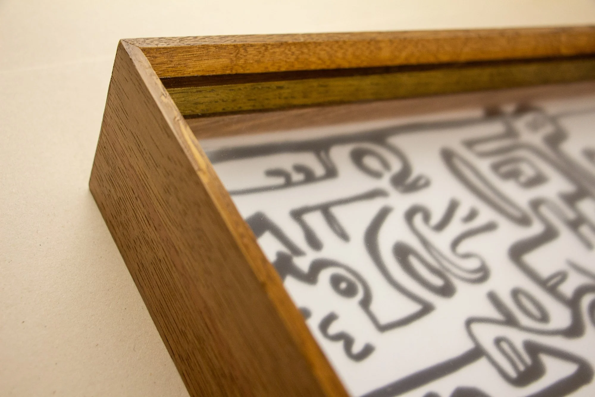 Veiled Alchemist 002 frame detail: angled corner view from above, showing the top edge, inner reveal, and the layered transition from the outer elm tone toward the red-toned inner section around the glazing.