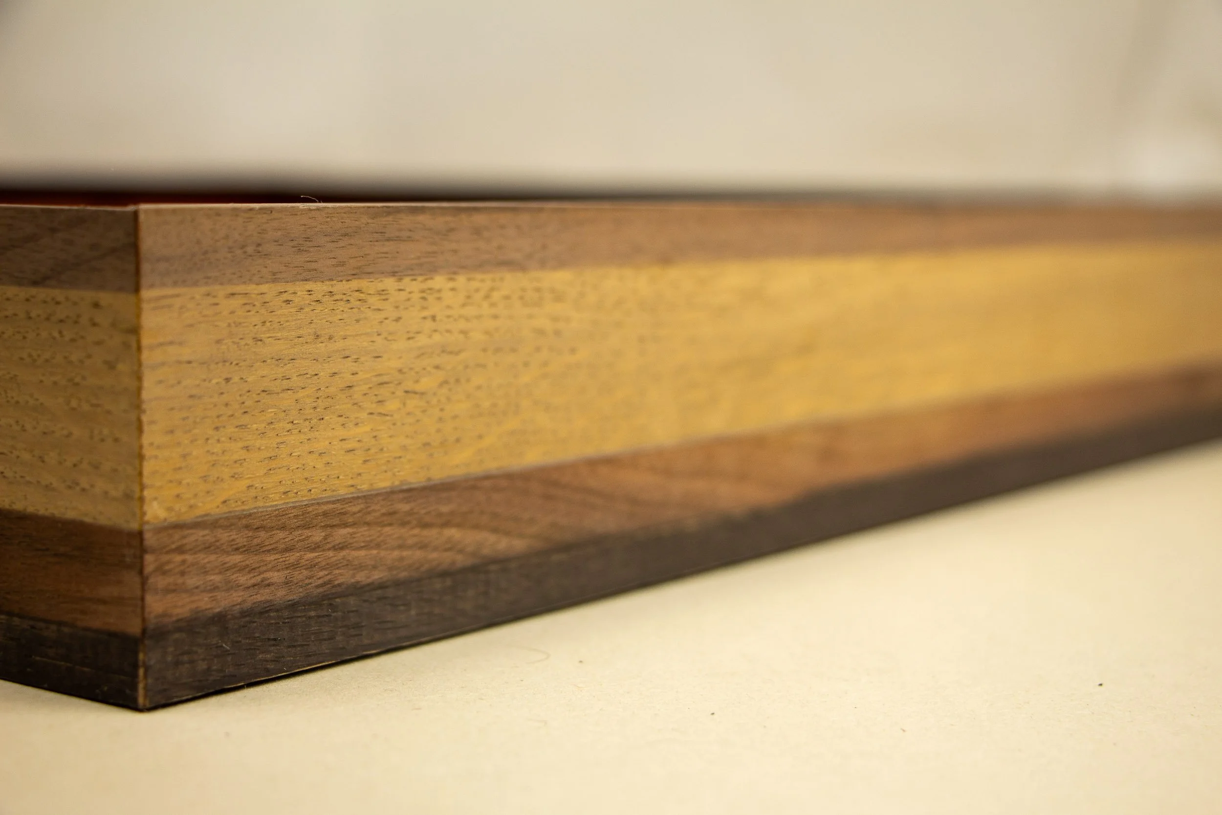 Mêlée of Discovery 001 frame: straight-on profile detail emphasizing the horizontal rhythm of the banded construction, where dark and light tones move across the frame in a measured sequence.