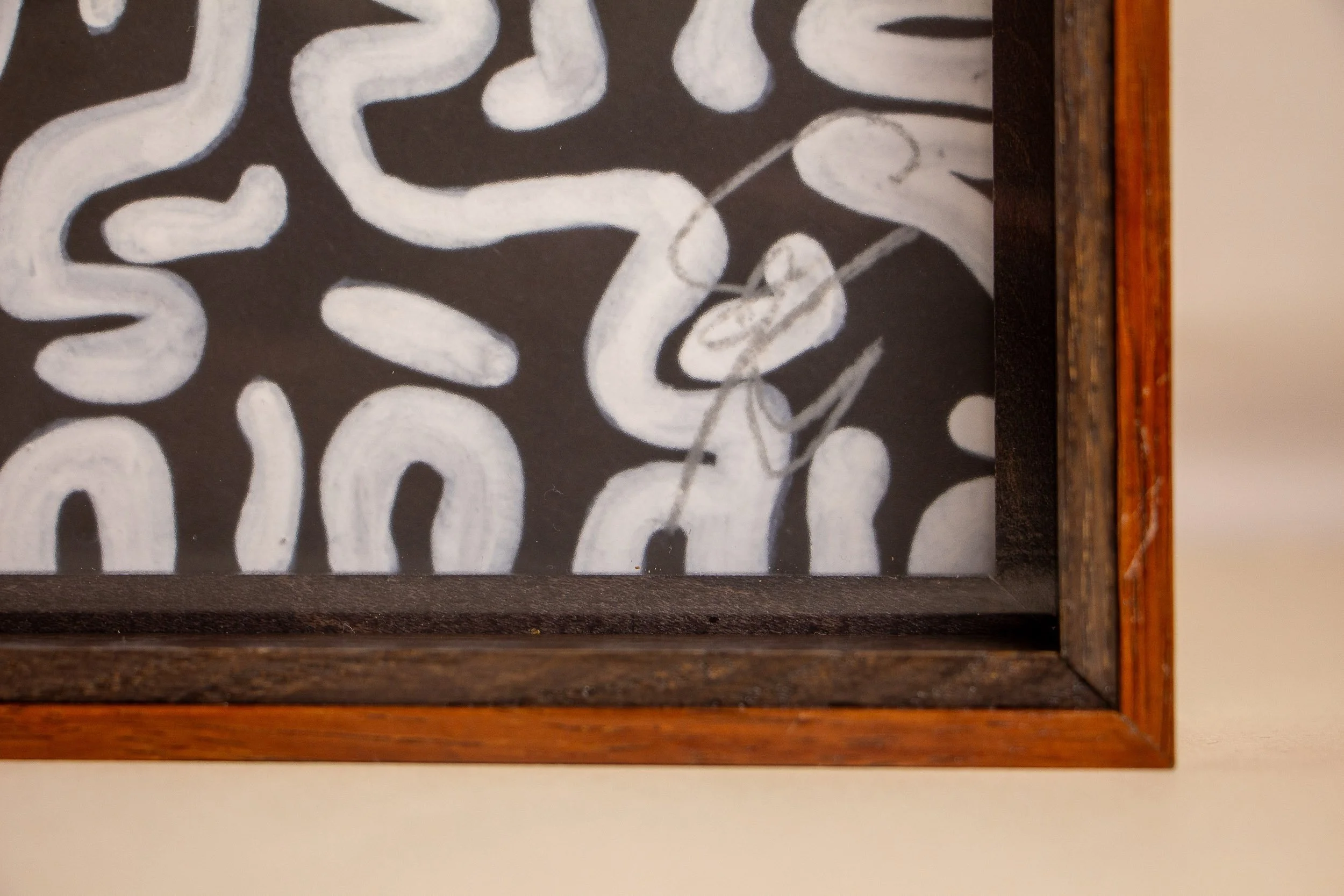 Turbulent Aegis 003 frame detail: close-up of the lower corner of the framed artwork, showing the warm outer band, dark inner frame, the artist’s signature behind the glass, and the precise layered finish of the construction.