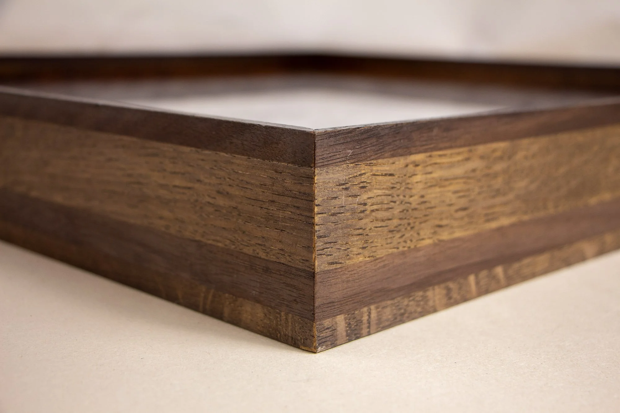 Luminous Parallax 001 frame: side profile close-up of the frame construction, highlighting the narrow top lip and the horizontal layering of darker and lighter wood tones across the depth of the frame.