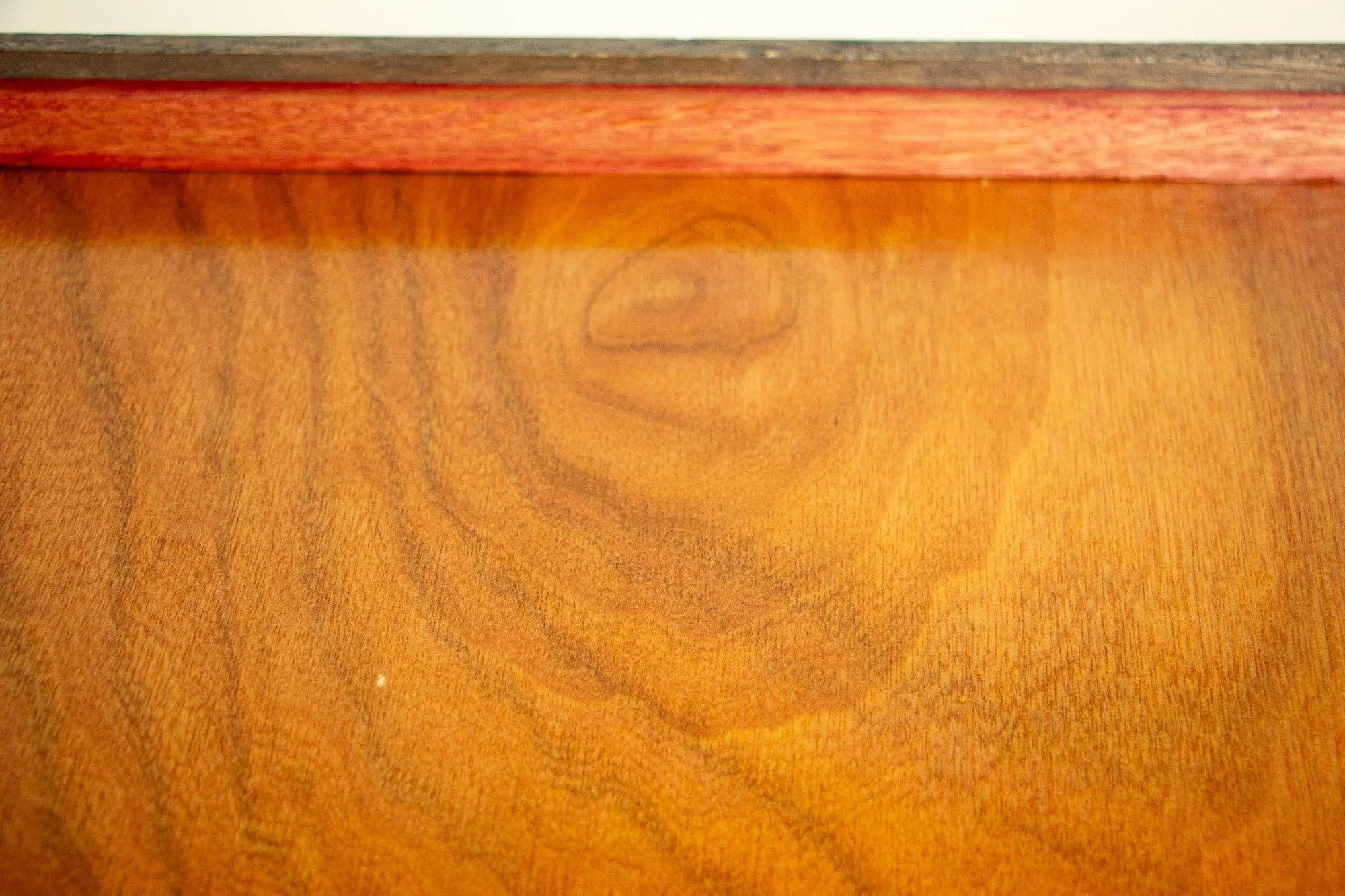 Luminous Parallax 002 frame: close-up of the reverse side, highlighting the flowing grain of the meranti plywood back panel beneath the red-toned inner rim and dark frame edge.