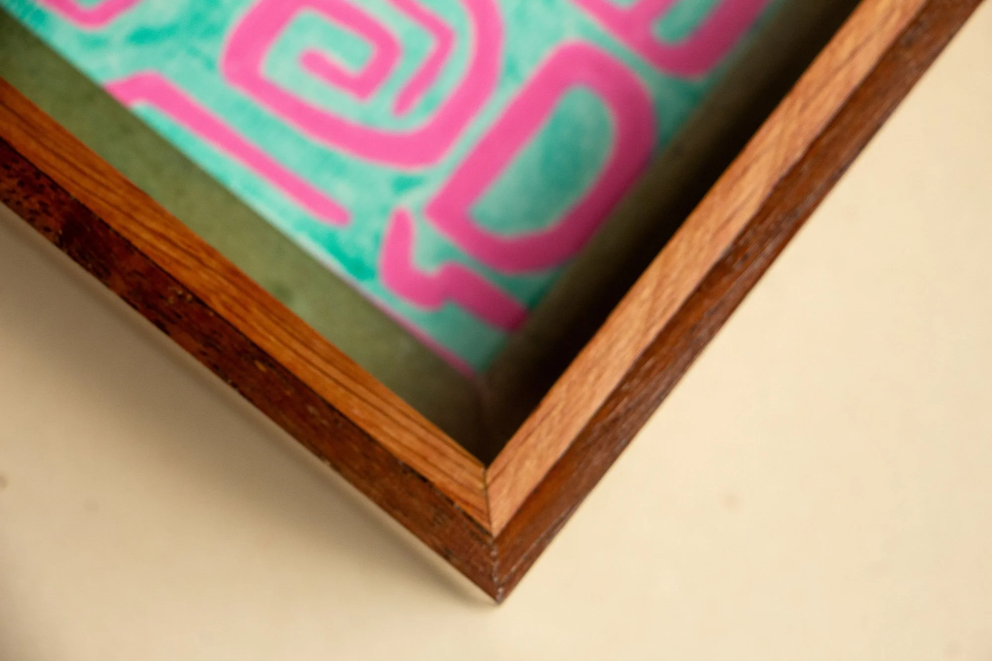 Unseen Signifiers 004 frame detail: top-down corner view highlighting the precise mitre joint, reddish outer frame, olive-green inner reveal, and the turquoise-and-pink artwork just inside the glazing. mahogany, oak and beech wood.