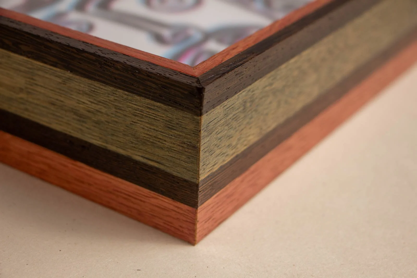 Silence’s Caesura 001 frame: outside mitre, three-tier lamination with a dark wengé cap, olive-stained oak field and a warm mahogany/padauk base; clean 45° join