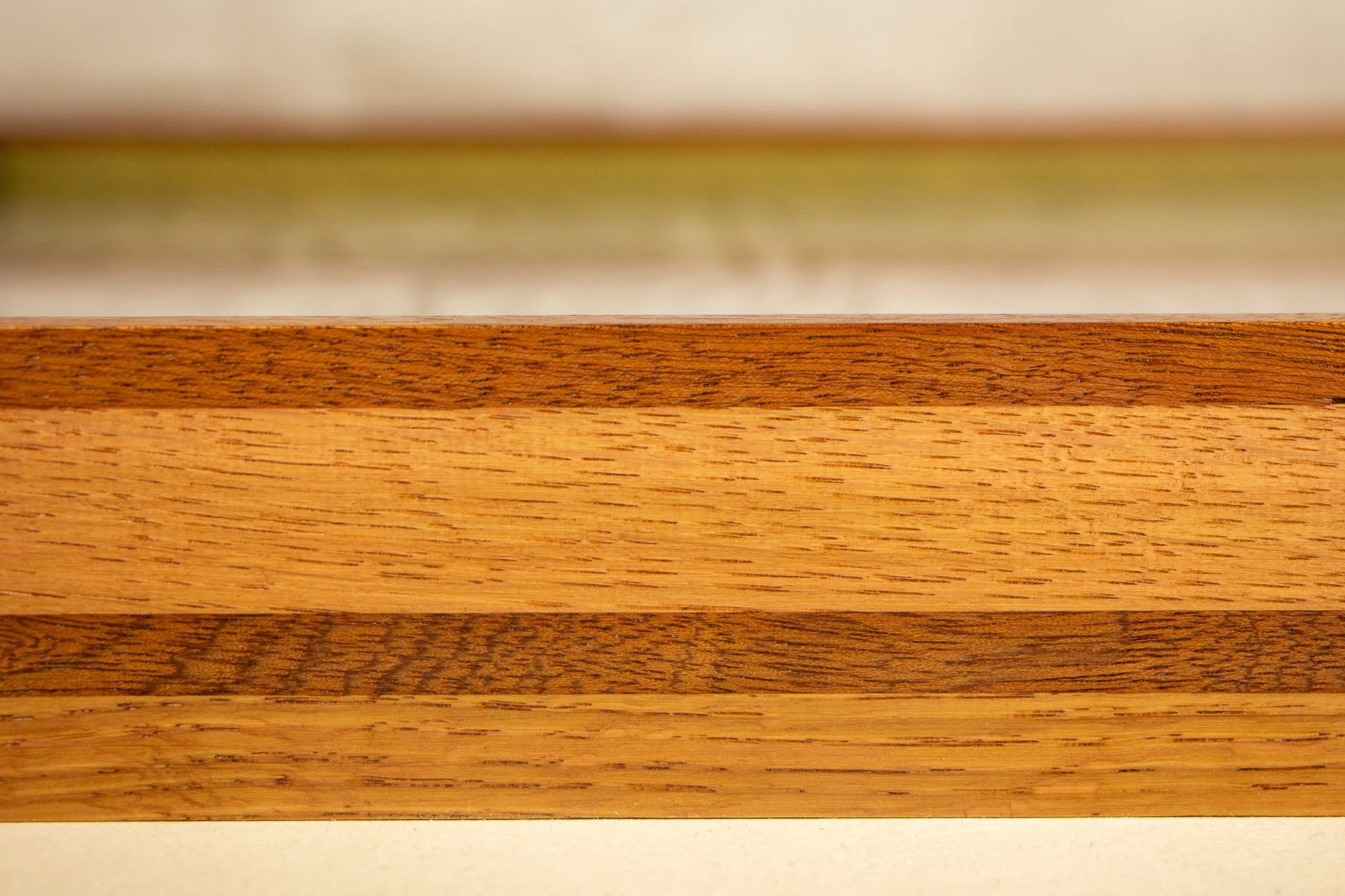 Resonant Syntax 001 frame: frontal detail of the laminated frame construction, with alternating colored oak and mahogany bands, subtle grain variation, and a refined handcrafted finish