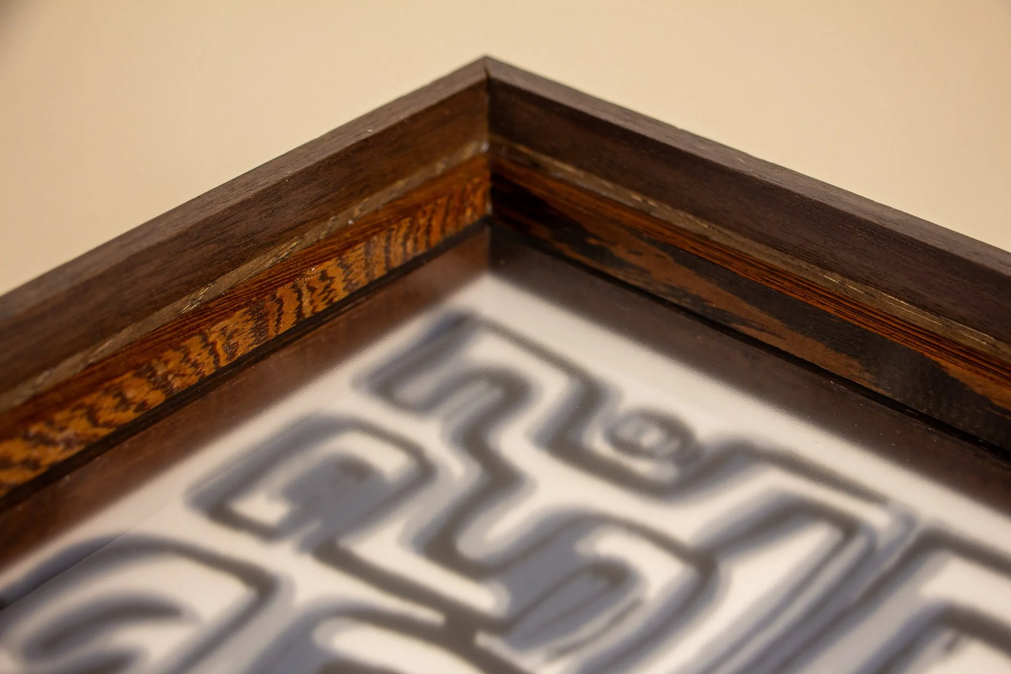 Luminous Parallax 004 frame: frontal side detail of the frame edge, highlighting the richly figured middle band and the restrained contrast between the darker top strip and warmer wood below.