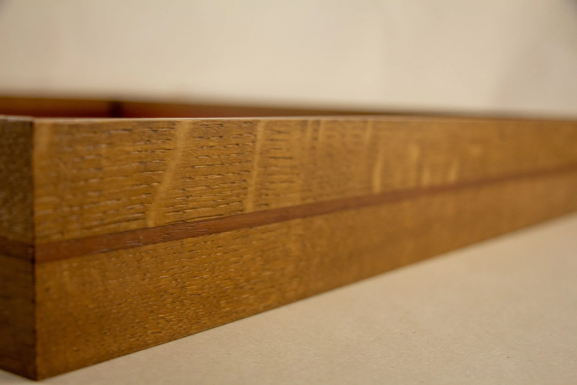 Veiled Alchemist 003 frame detail: long angled side view of the frame, emphasizing the calm wood grain, the narrow red-toned band, and the restrained depth of the handcrafted profile.