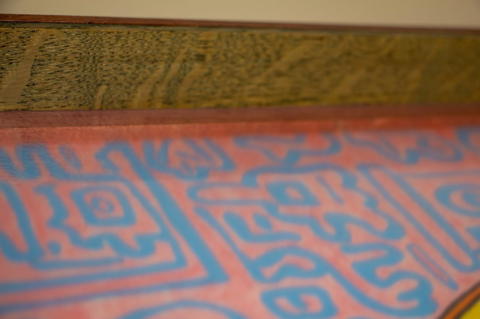 Unseen Signifiers 006 frame detail: macro close-up of the olive-green inner liner above the artwork, with the glass reflecting the pink and blue painted symbols beneath. mahogany, oak and beech wood.