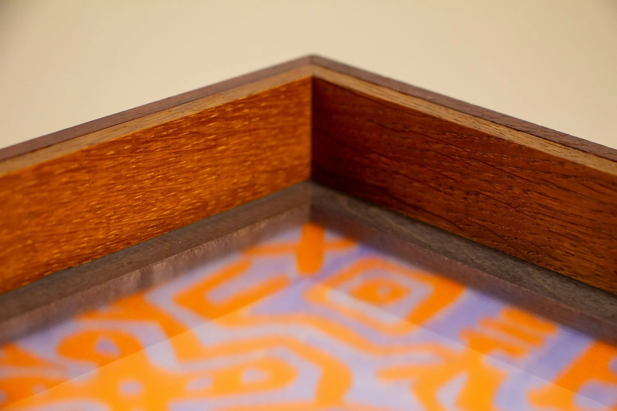 Unseen Signifiers 010 frame detail: top inside corner of the frame, showing the warm-toned wood surround, the darker inner liner, and the acrylic surface above the softly blurred artwork. mahogany, oak and beech wood.