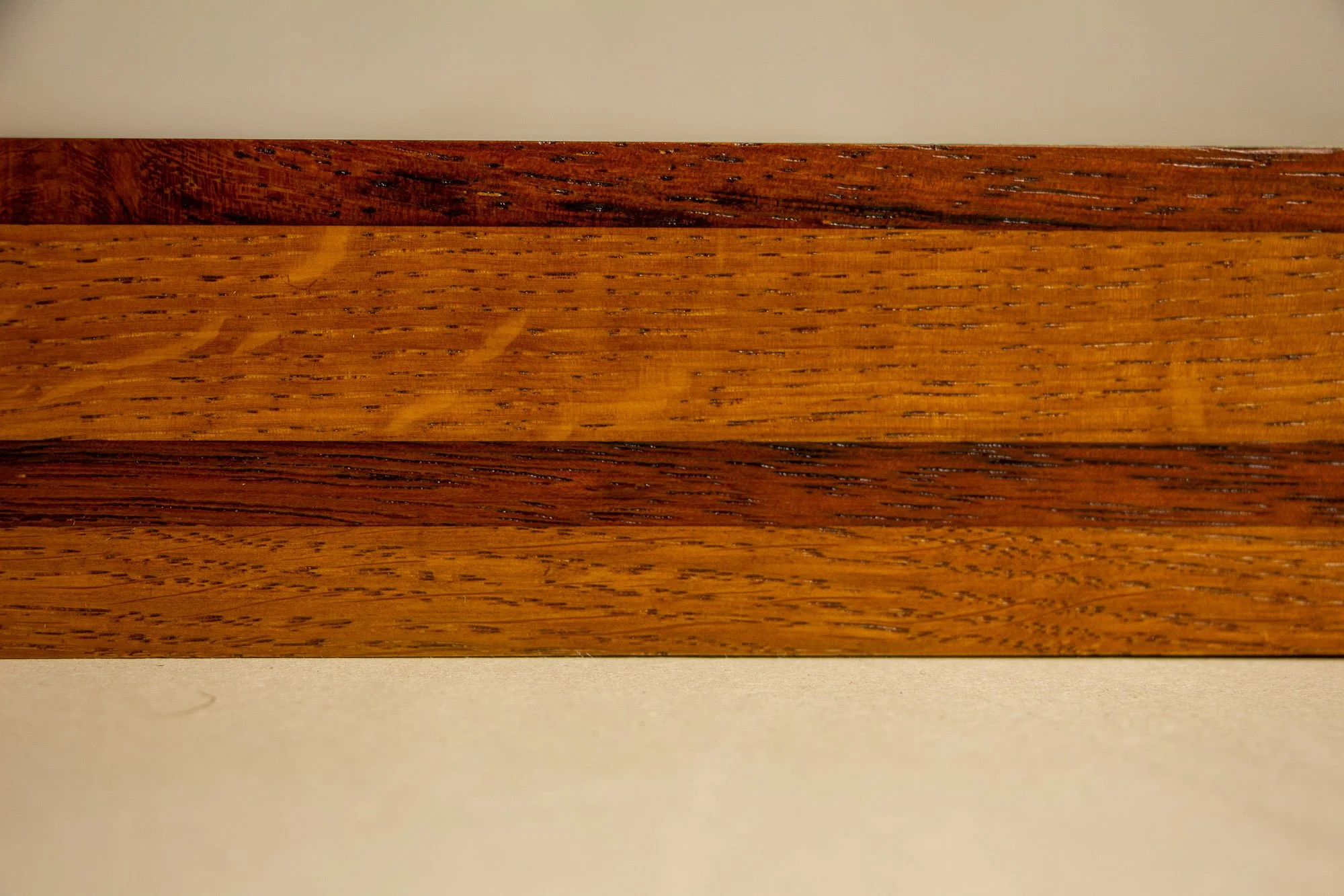 Unseen Signifiers 002 frame detail: straight-on close-up of the frame front, showing the layered banding, warm amber-brown finish, and pronounced linear grain. mahogany, oak and beech wood.