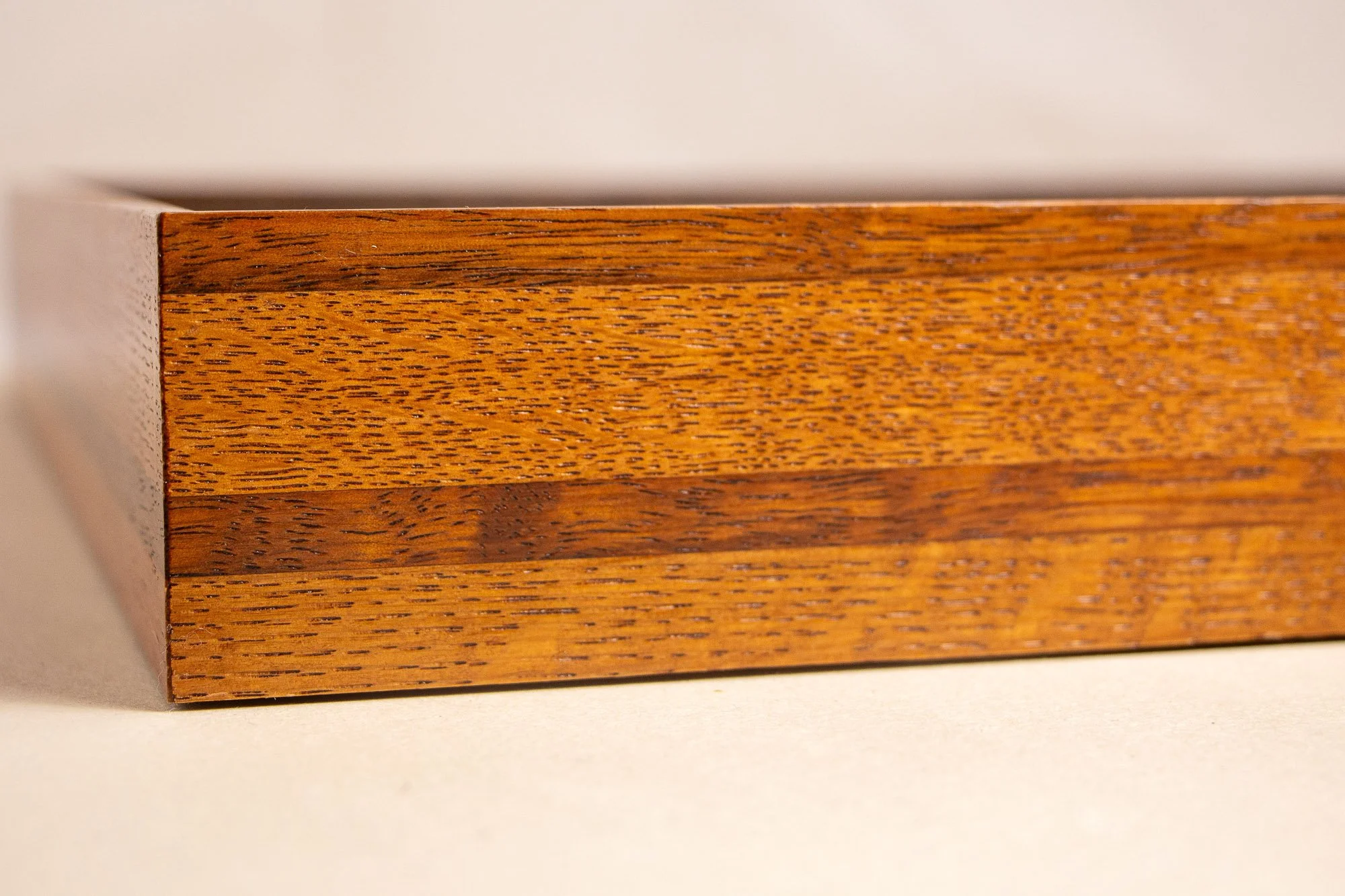 Turbulent Aegis 002 frame detail: close-up of the handcrafted frame’s side profile, showing the layered wood construction, fine grain pattern, and warm lacquered finish across the horizontal bands.