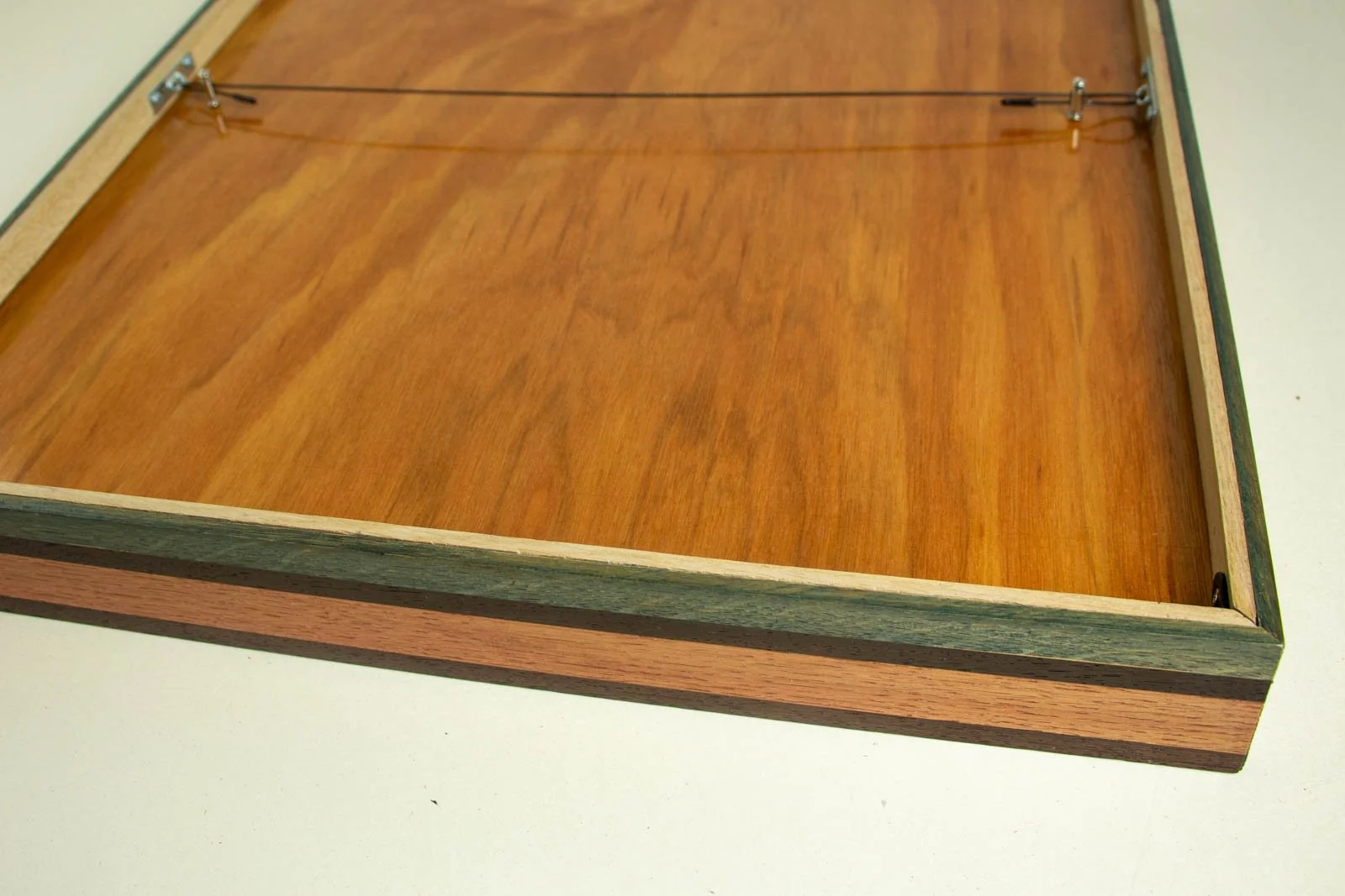 Silence’s Caesura 002 frame: reverse view, honey-toned backboard with steel plates; black coated hanging wire and brass T-toggle neatly recessed