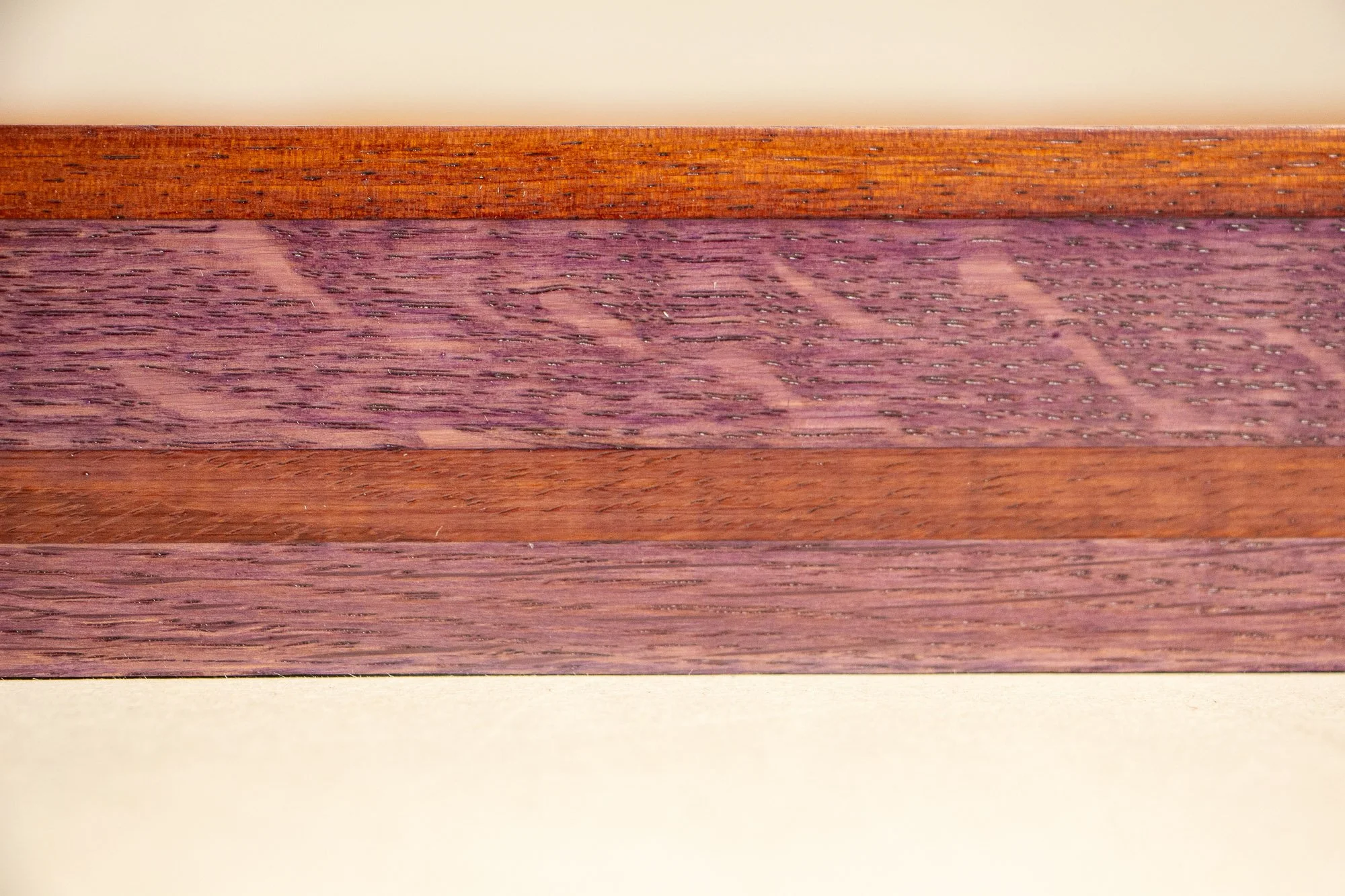 Unseen Signifiers 009 frame detail: straight-on close-up of the frame profile, showing a broad plum wood band crossed by a narrow warm brown strip beneath the slim top edge. mahogany, oak and beech wood.