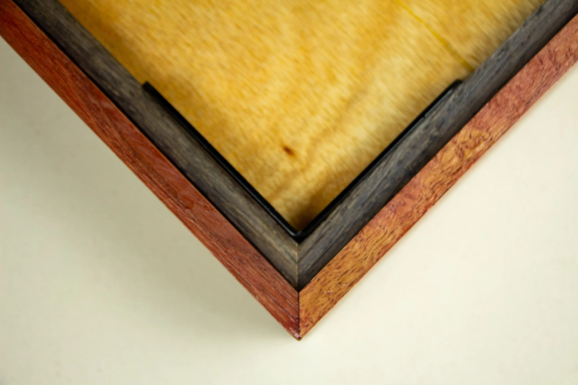 Resonant Syntax 003 frame: lower edge detail of the layered frame, with granada inner lip, green spacer, red outer band, and the artwork surface visible above