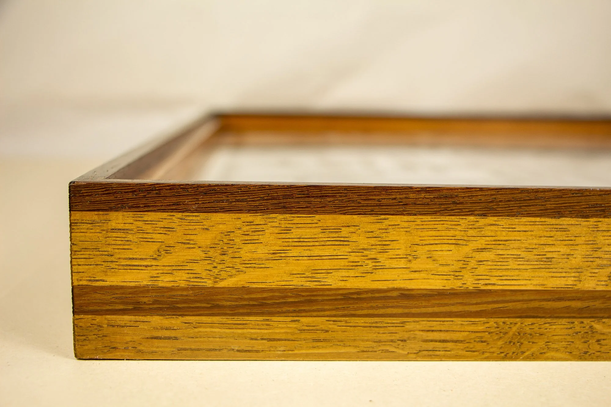 Elusive Cocoon 002 frame: angled side detail of the frame construction, emphasizing the layered profile, the warm golden oak-toned band, and the darker upper edge.