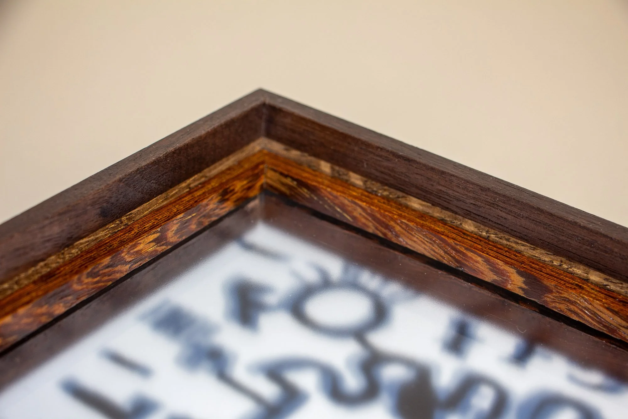 Luminous Parallax 003 frame: close-up of the upper frame edge, emphasizing the dark outer structure, fine intermediate seam, and the vivid figured inner band above the glazed artwork.