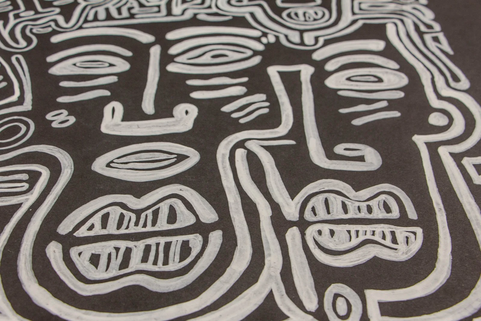 Metamorphic Entwining 003 detail: twin front-view heads with interlocking nose bridge and lips hatched like teeth; white ink on black paper