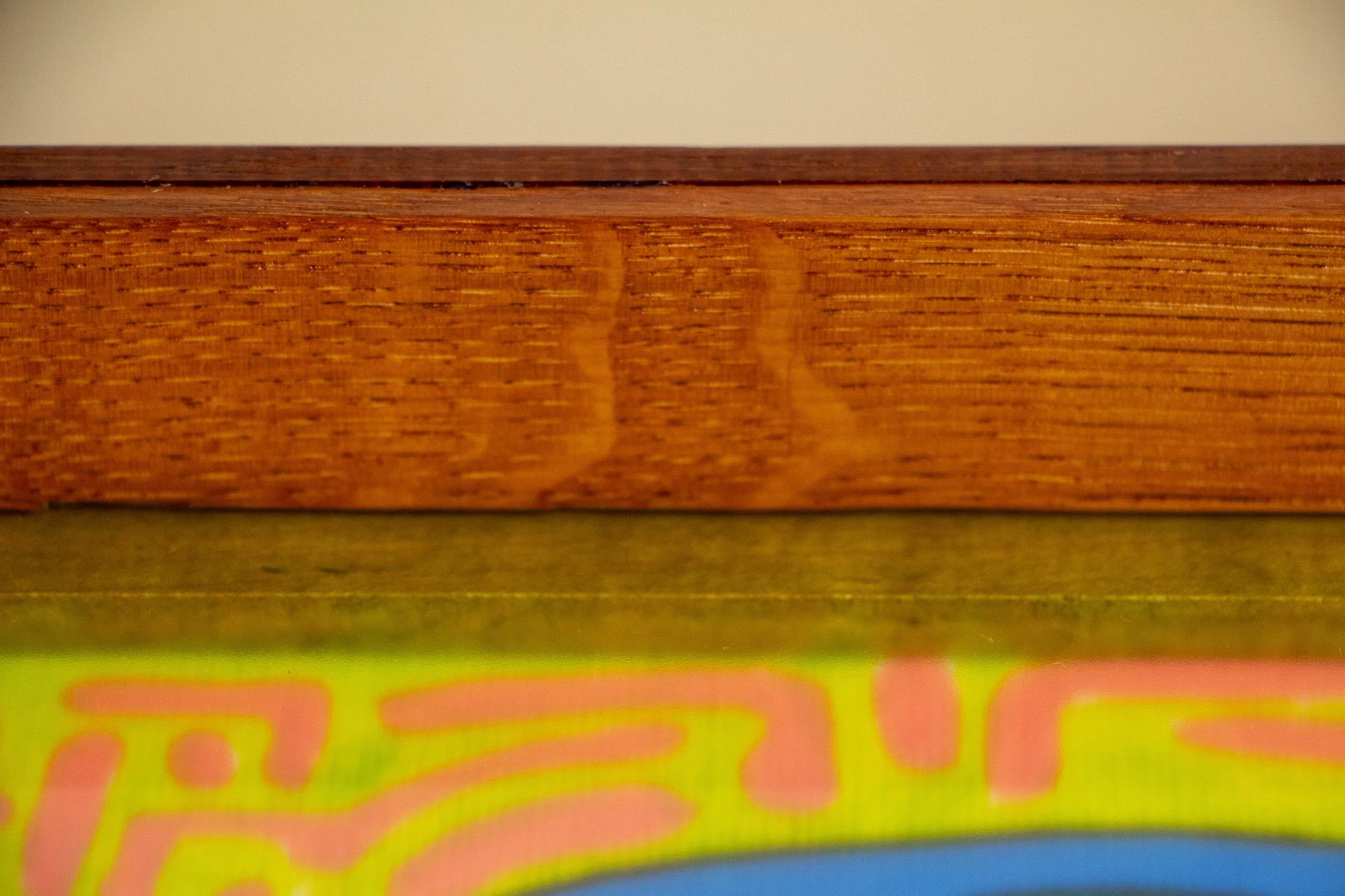 Unseen Signifiers 009 frame detail: extreme close-up of the upper frame edge, showing the slim polished top lip above the warm brown wood band and the acrylic front. mahogany, oak and beech wood.