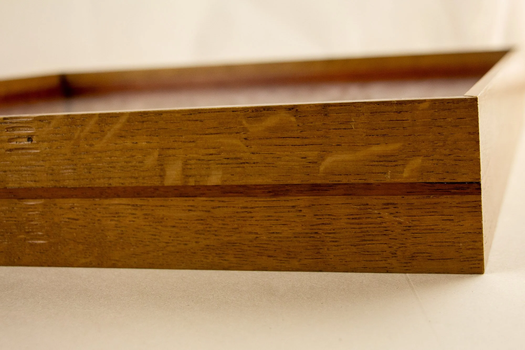 Veiled Alchemist 001 frame detail: close-up of the front corner of the frame, emphasizing the clean craftsmanship, the smooth lacquered finish, and the restrained movement of the wood grain across the layered construction.