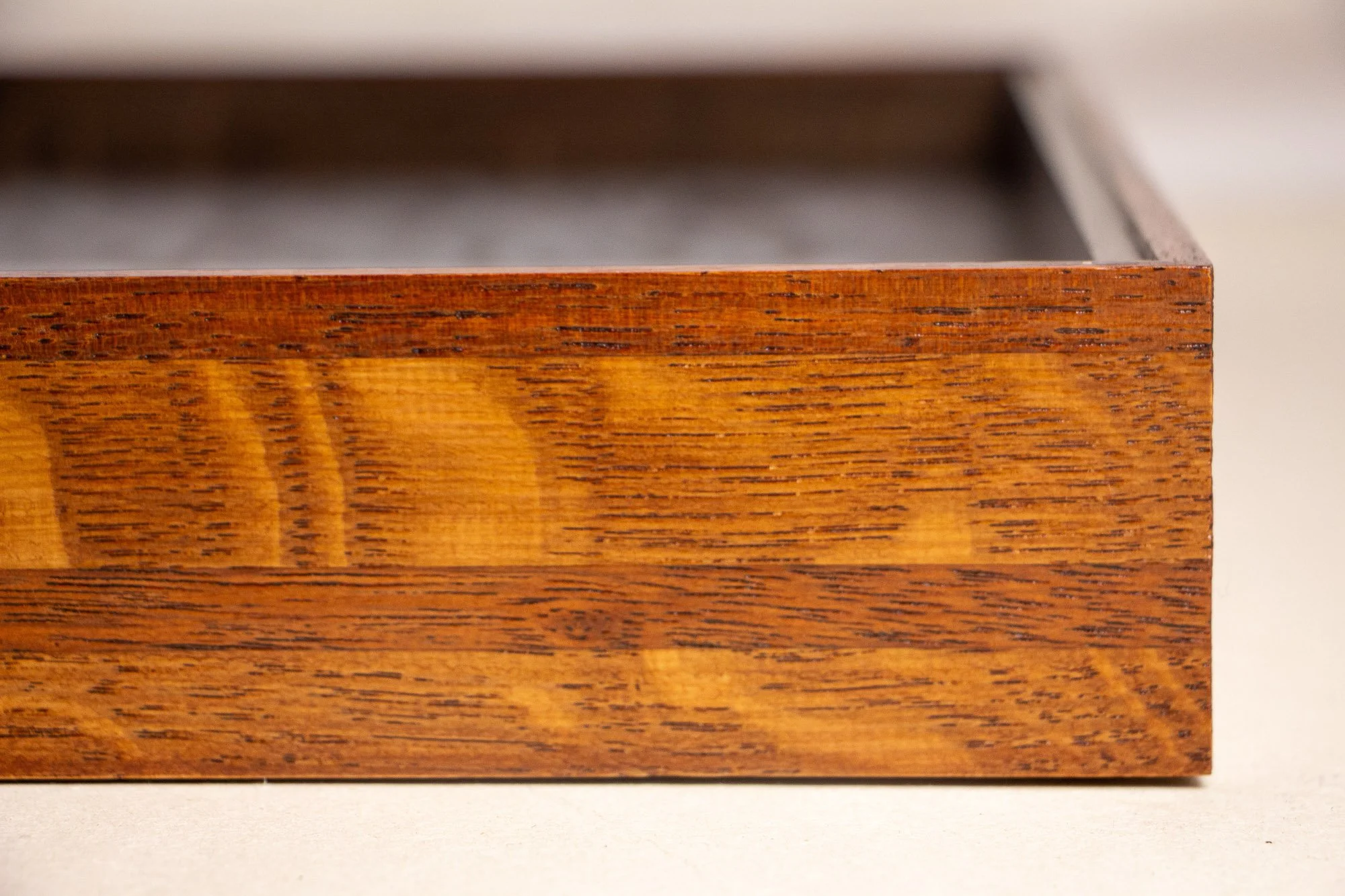 Turbulent Aegis 001 frame detail: angled corner close-up of the frame, highlighting the crisp join, warm lacquered surface, and the layered wood tones moving toward depth.