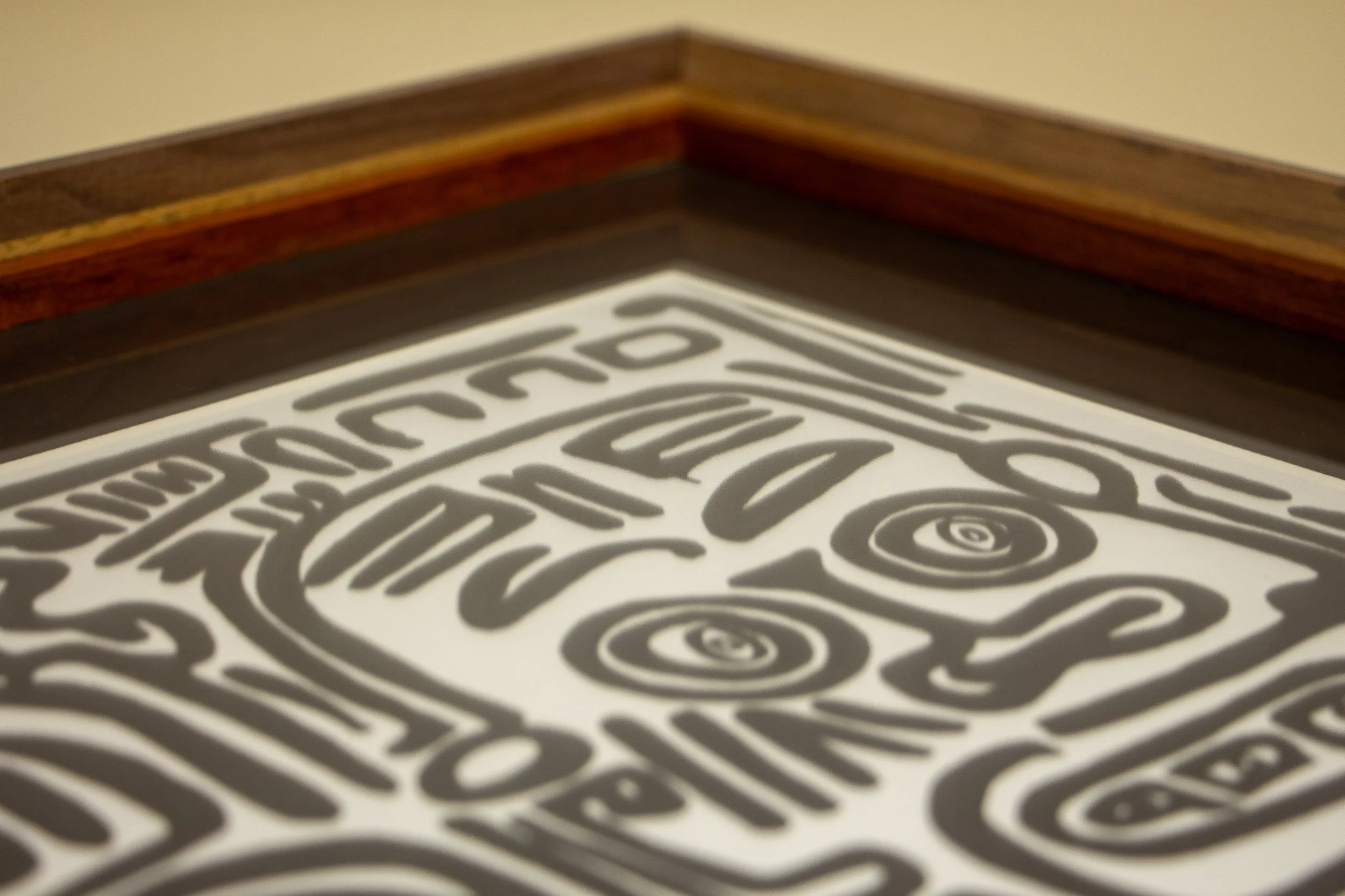 Mêlée of Discovery 004 frame: inner corner view with the artwork beneath glazing, highlighting the reddish-brown inner lip and the layered frame structure around it.