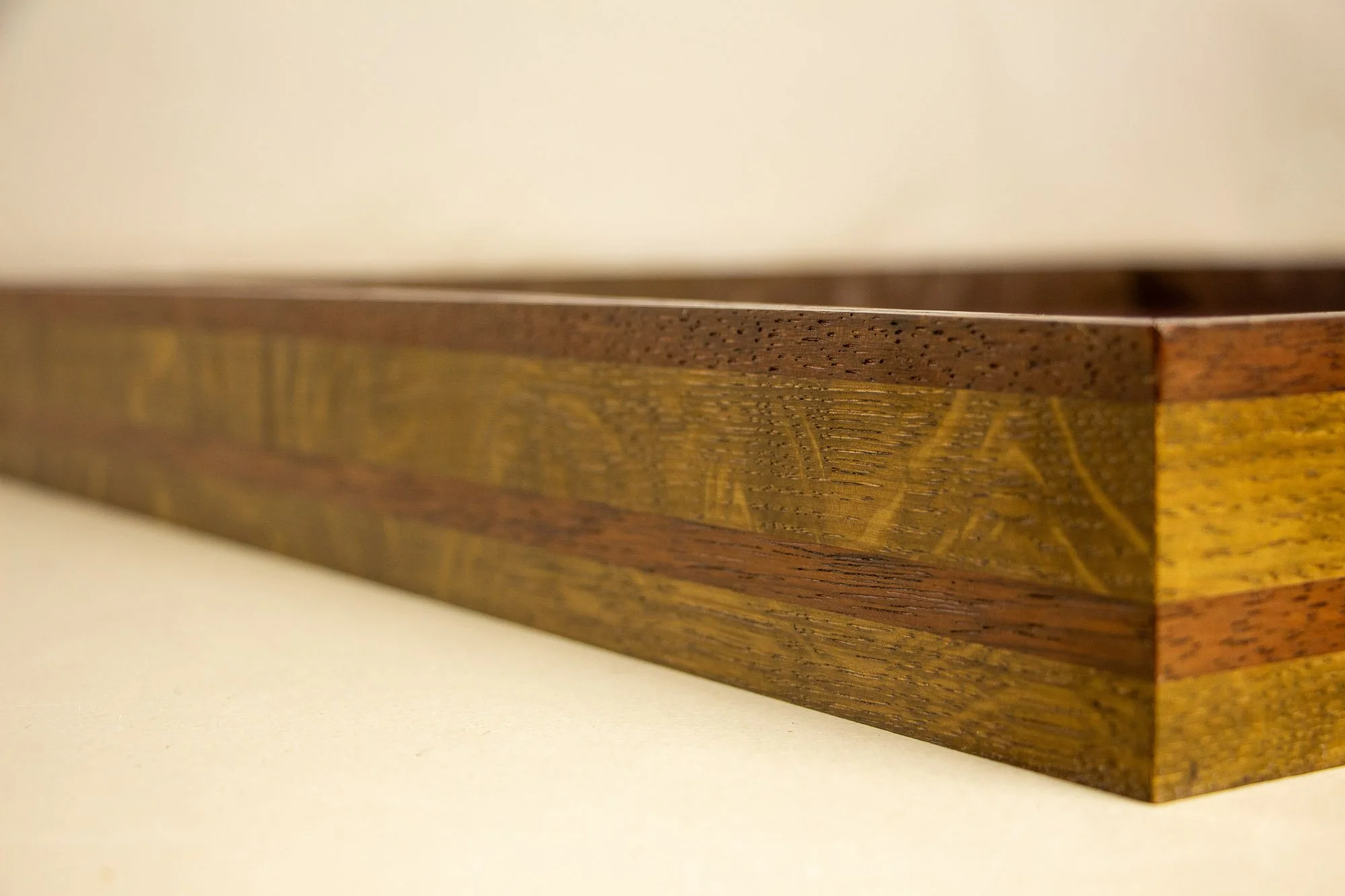 Unseen Signifiers 007 frame detail: angled side view of the deep frame profile, showing the layered wood construction and alternating dark olive-brown and reddish-brown bands. mahogany, oak and beech wood.