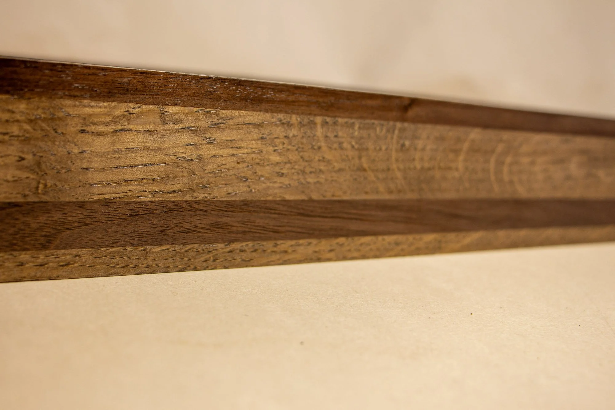 Luminous Parallax 003 frame: elongated side-profile detail highlighting the horizontal banding, subtle grain shifts, and the restrained brown-black palette of the layered frame body.