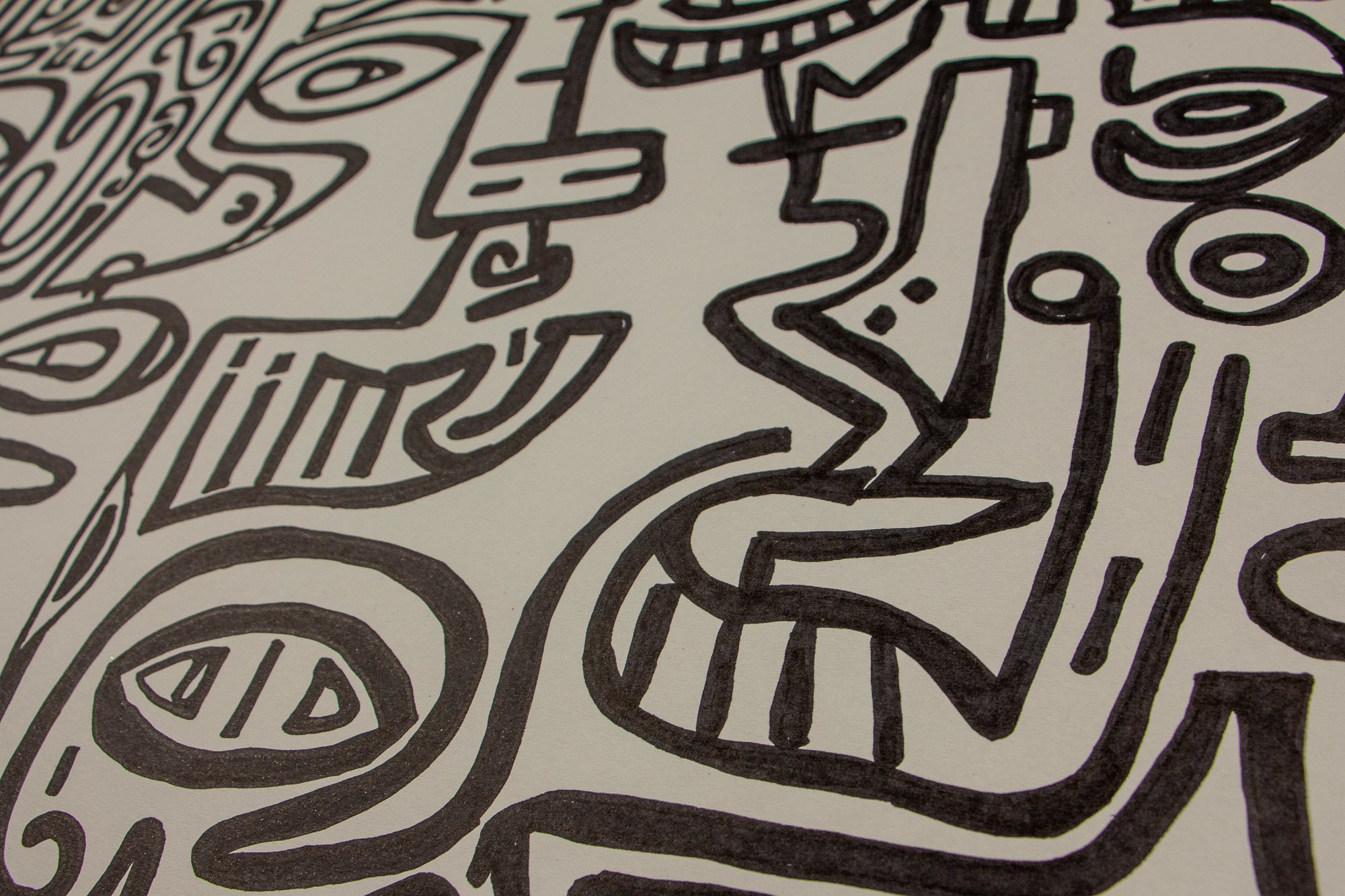 Elusive Cocoon 004 detail: angled close-up of interlocking abstract figures with tooth-like mouth forms, elongated nose contours, and rounded eye motifs across the white paper surface.