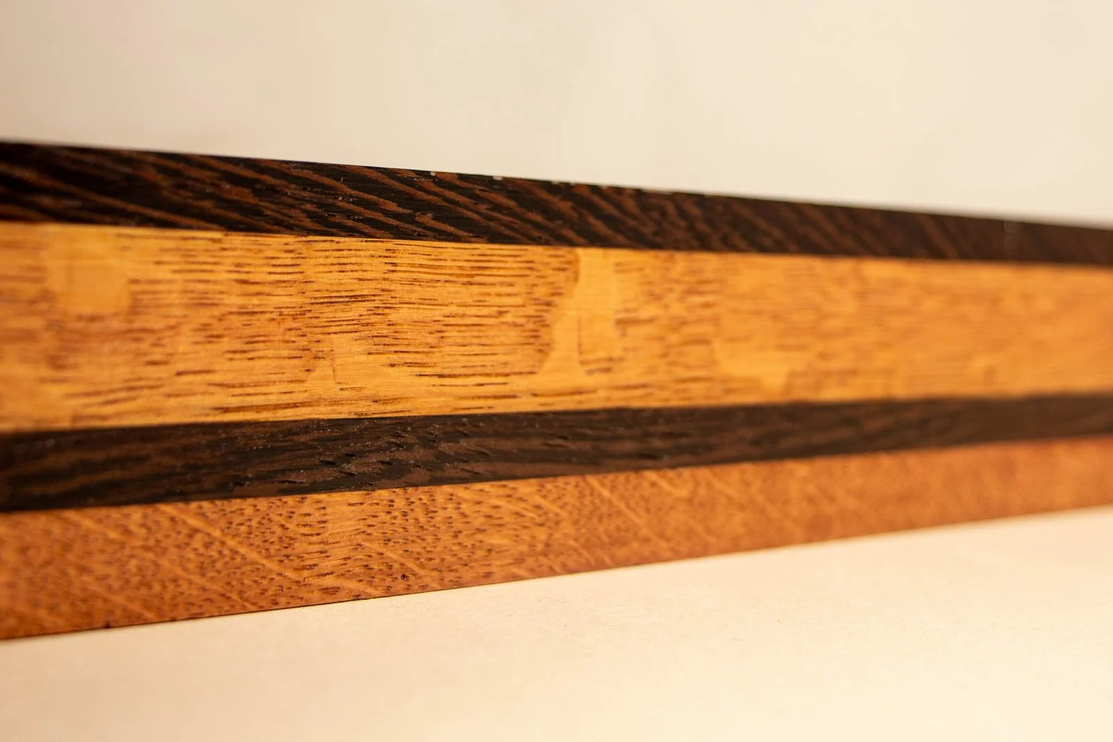 Formless Equation 003 frame: layered rails with dark wengé top, golden oak band, and reddish oak base, side perspective