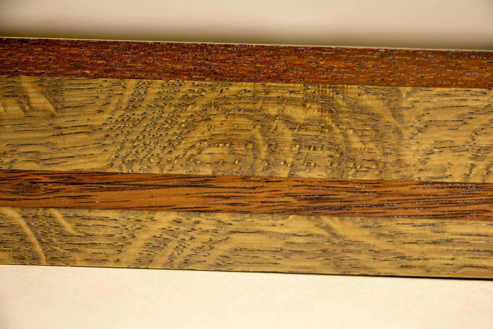 Unseen Signifiers 001 frame detail: close-up of the frame profile, showing the polished reddish upper edge, the lighter oak body beneath it, and the darker wood strip set across the middle. mahogany, oak and beech wood.