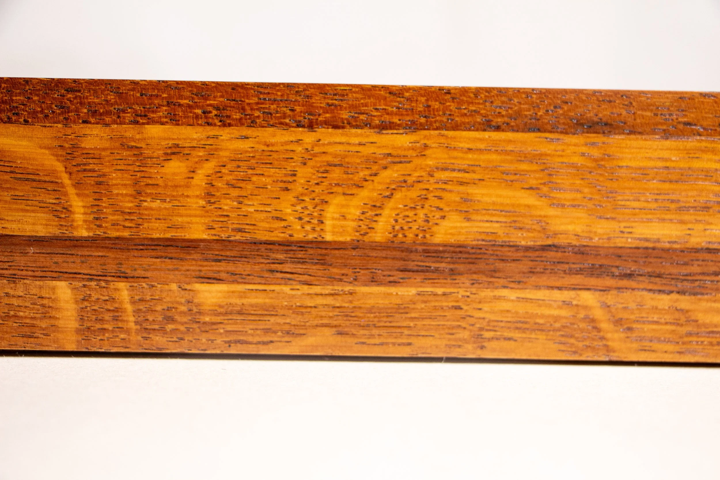 Turbulent Aegis 003 frame detail: close-up of the frame side showing the layered wood bands, distinctive grain pattern, and warm lacquered sheen that give depth and structure to the frame.