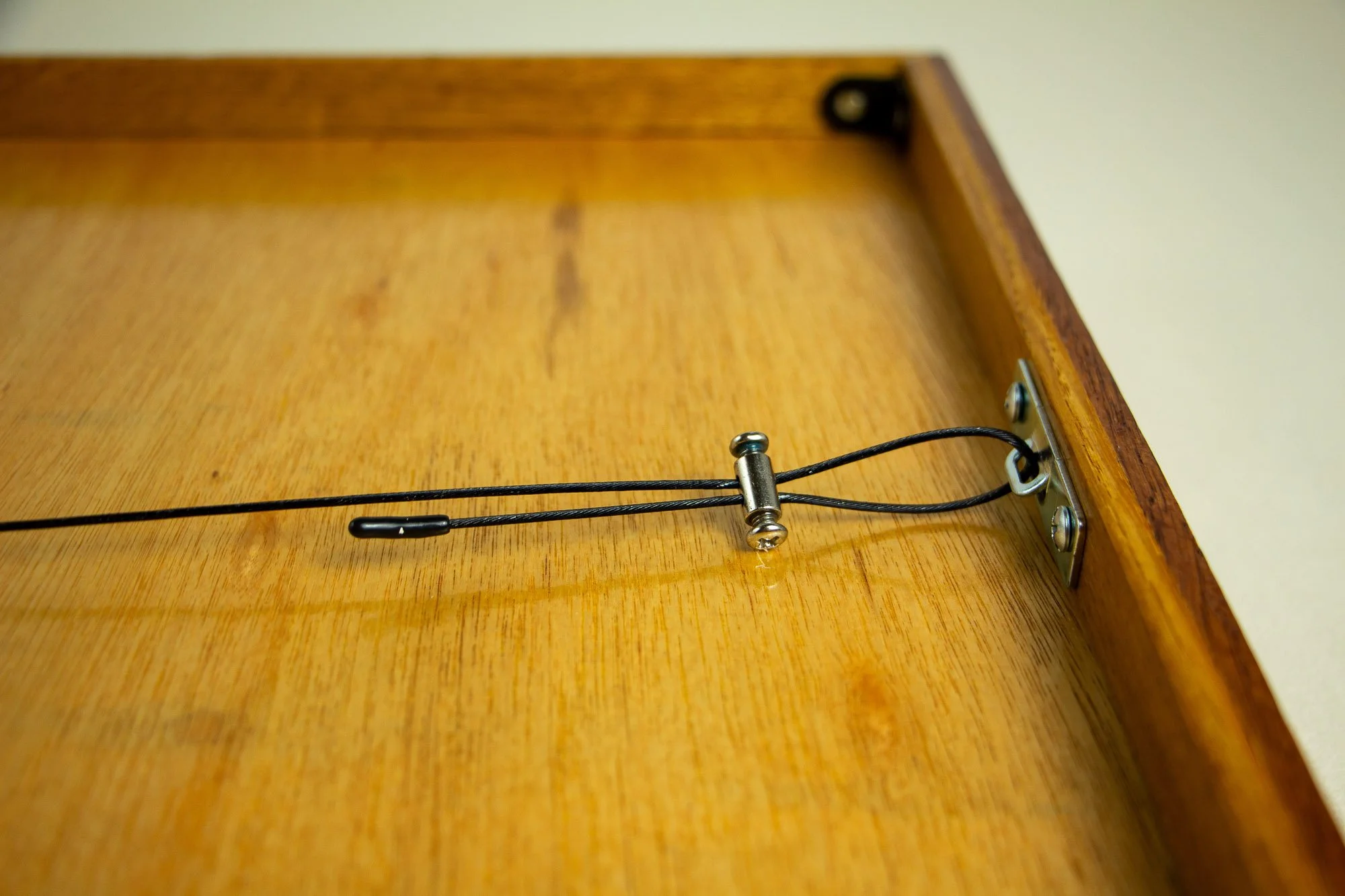 Turbulent Aegis 002 frame detail: rear close-up of the hanging system, showing the metal plate, black hanging wire, and fastening hardware mounted into the inner wooden frame.