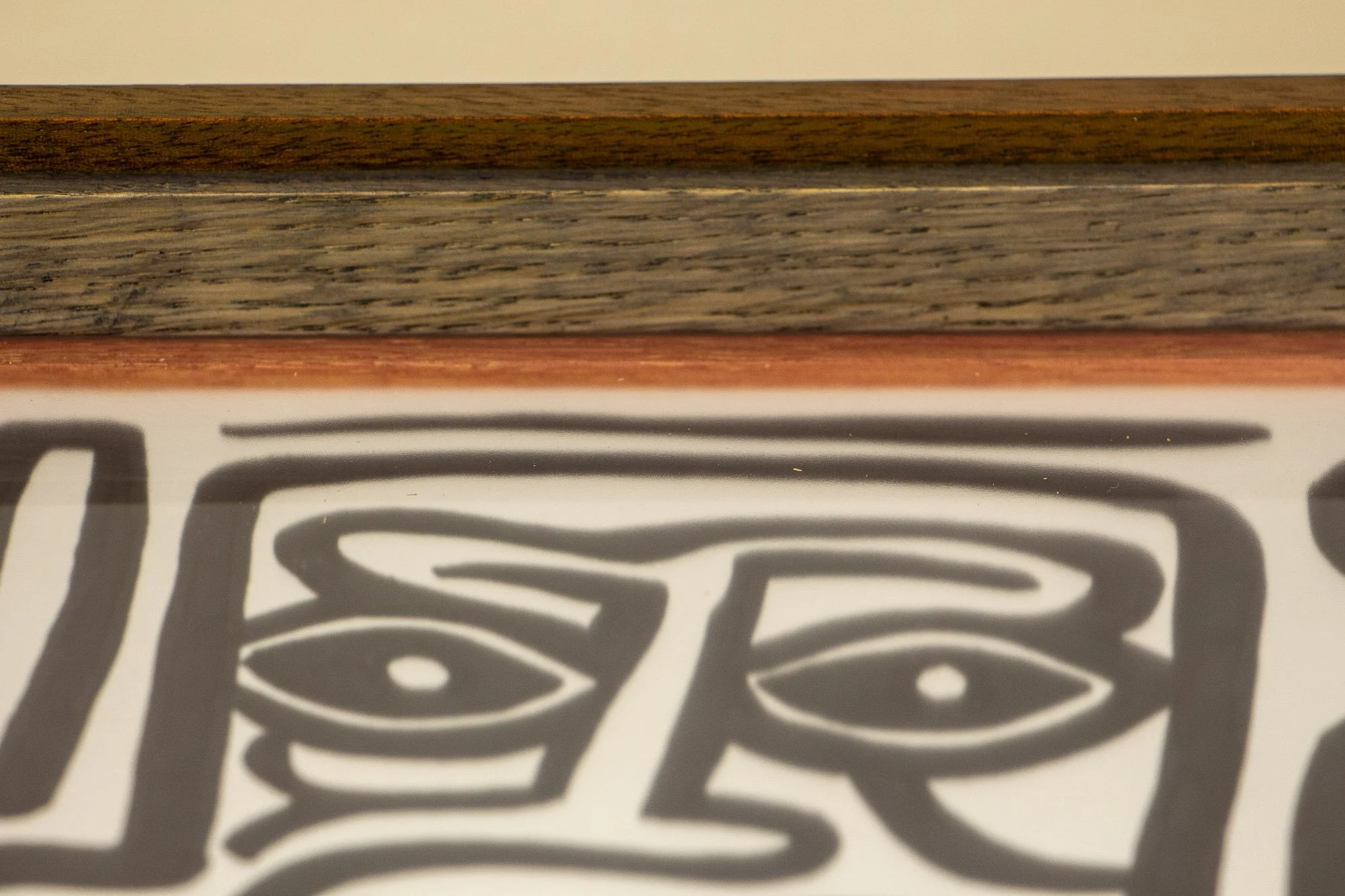 Resonant Syntax 004 frame: upper edge detail with warm granada-red outer band, darker inner oak layer, and a red inner lip bordering the artwork under glass